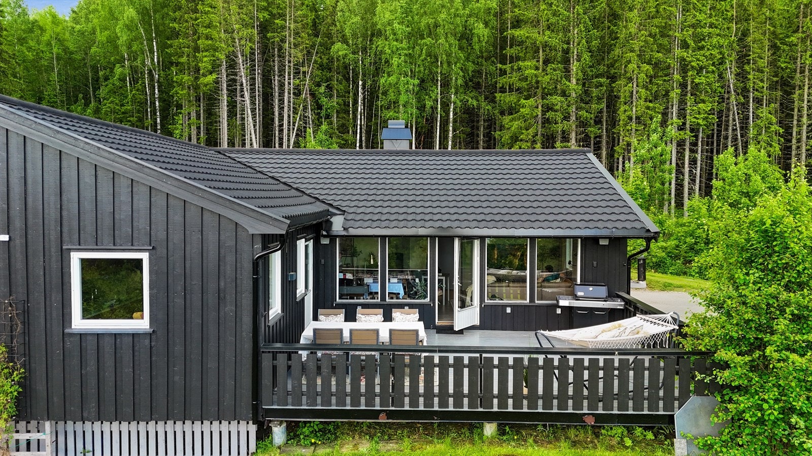 Fra denne vinkelen får man et godt inntrykk av boligens harmoniske plassering i terrenget, omgitt av frodig vegetasjon. Galleribilde