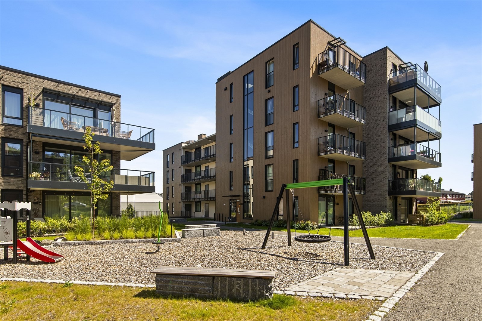 Tomten er pent opparbeidet med hyggelig fellesareal og grusede internveier mellom bygningene. Lekeplass. Galleribilde
