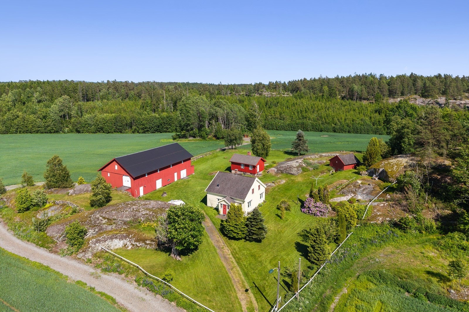 Eiendommen ligger flott til i et lett skrånende og åpent terreng med høyere terrengformasjoner mot øst, noe som bidrar til en lun og skjermet atmosfære på tunet. Galleribilde