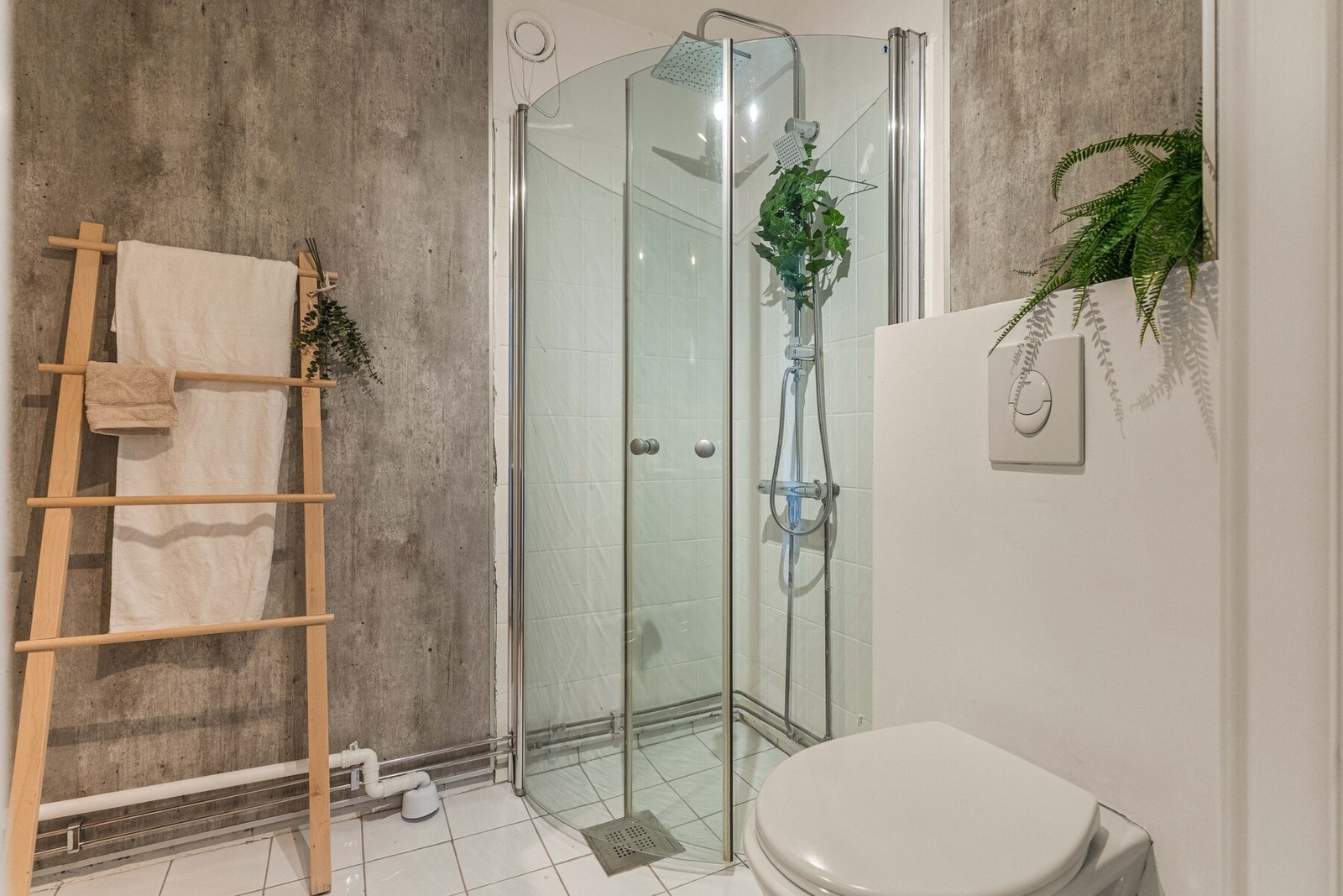 Badet er innredet med vegghengt toalett og dusjsone med innfellbare glassdører. Stilrene fargekontraster skaper et harmonisk og gjennomført uttrykk. Galleribilde