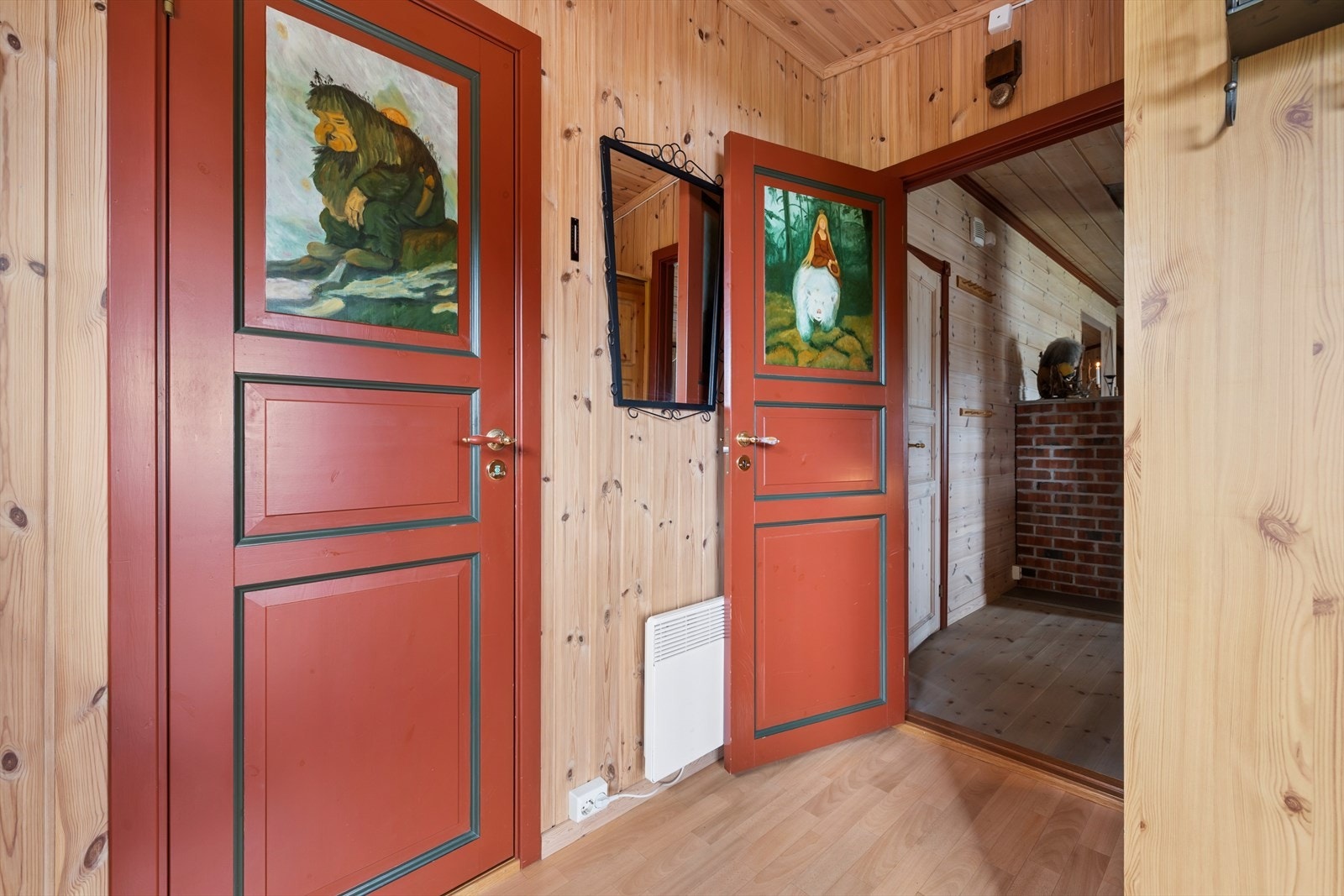 Fra verandaen på sørvestsiden kommer man inn i entréen med plass til å henge fra seg yttertøy. Furu fyllingsdører fra 2007 er håndmalt med motiver i tradisjonell stil. Galleribilde