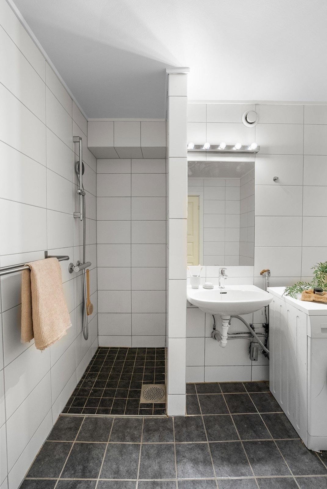 Badet er utstyrt med toalett, servant med innmurt speil og overliggende belysning, dusjnisje samt opplegg for vaskemaskin. Galleribilde