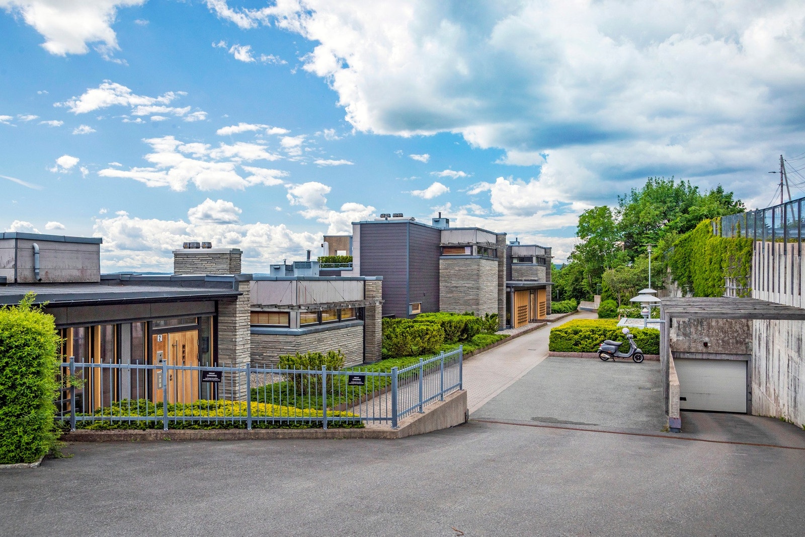 Velstelte fellesarealer i sameiet med belegningsstein, sittegrupper, sandkasse, gressplen og frodig beplantning. Galleribilde