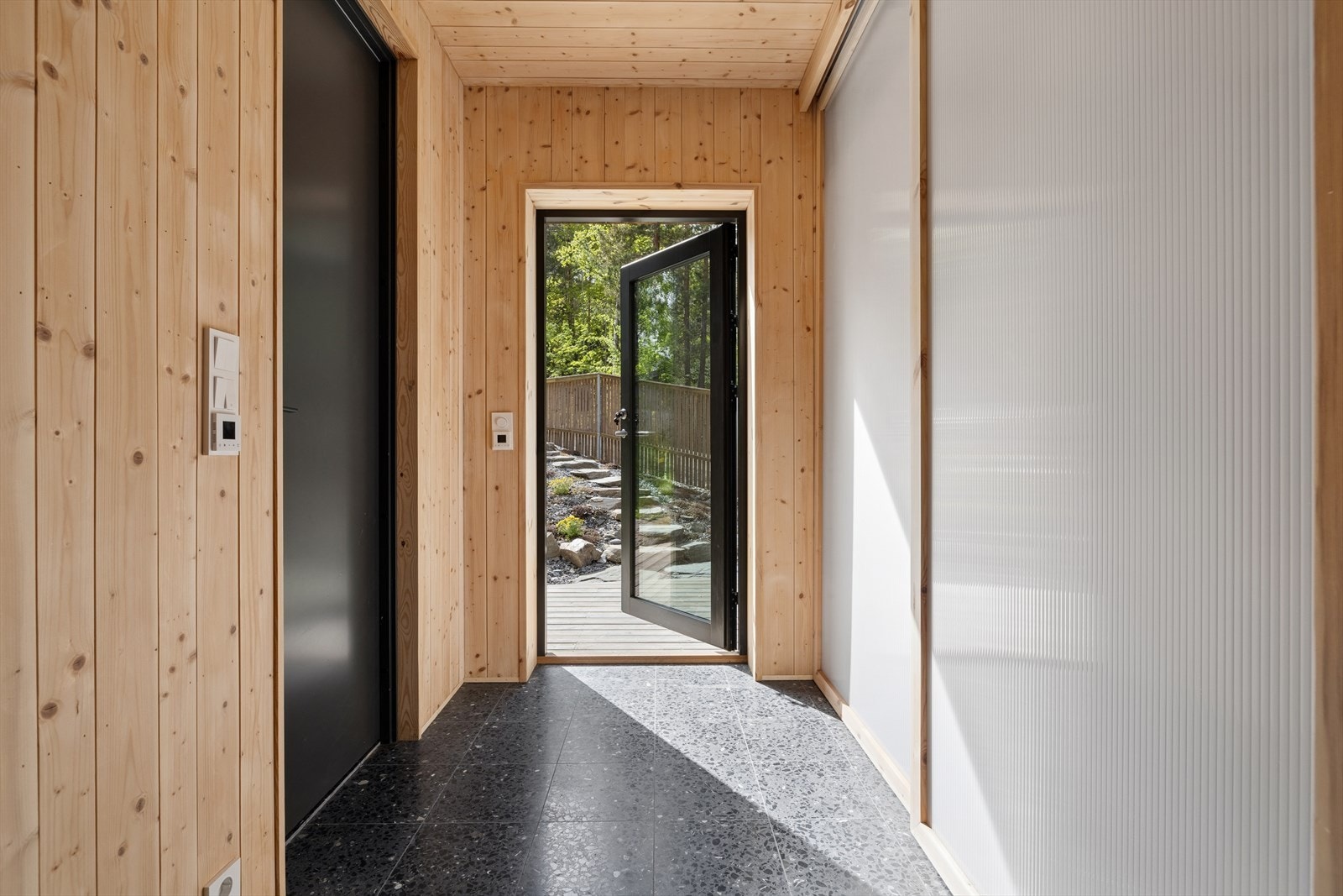 Man ønskes velkommen inn til entréen i første etasje. Her er det solide terrazzofliser og romslig skyvedørsgarderobe. Gjestebad og vaskerom til venstre. Galleribilde
