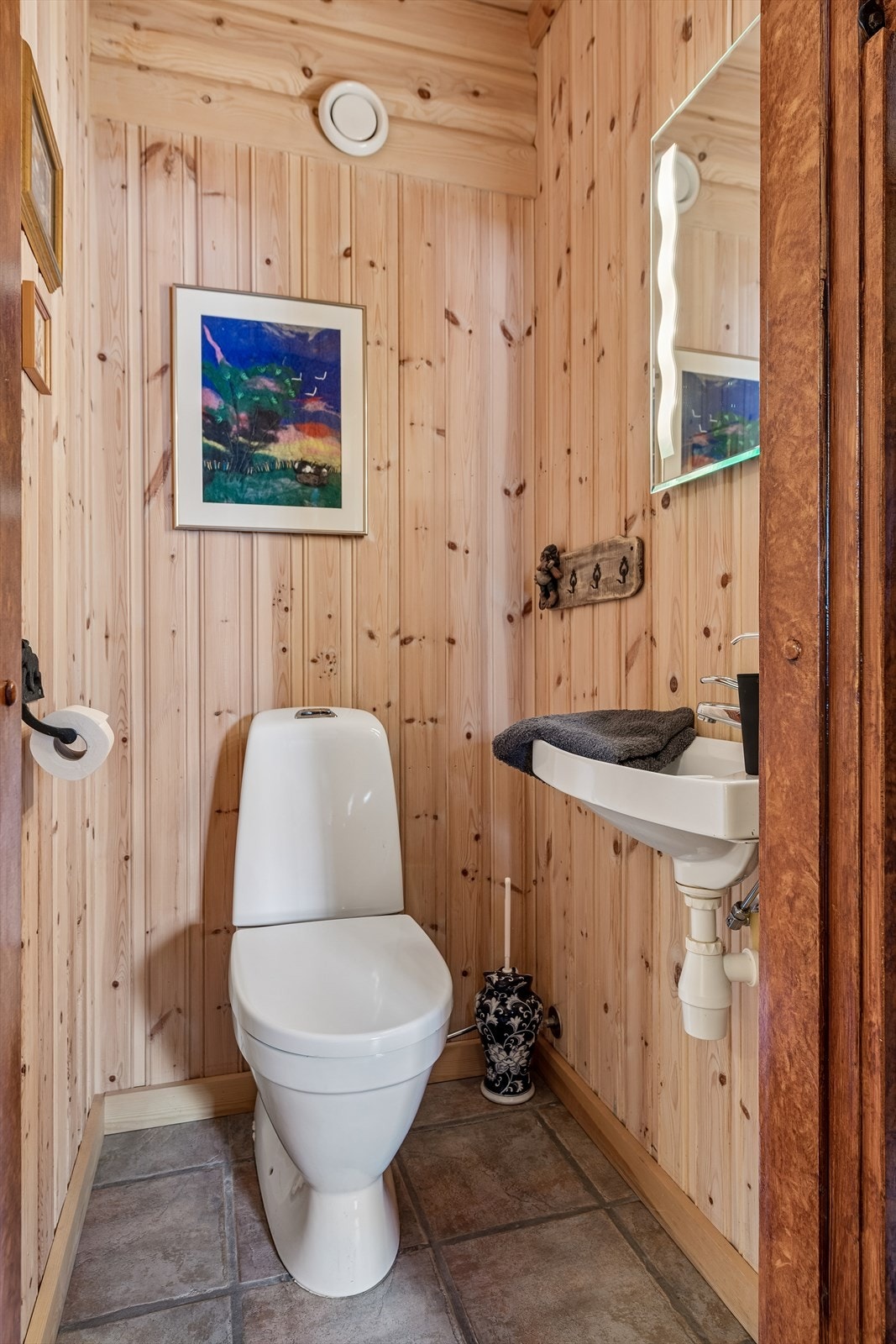 Toalettrommet har gulv med fliser og vegger med behandlet panel, samt mekanisk avtrekk for ventilasjon. Galleribilde