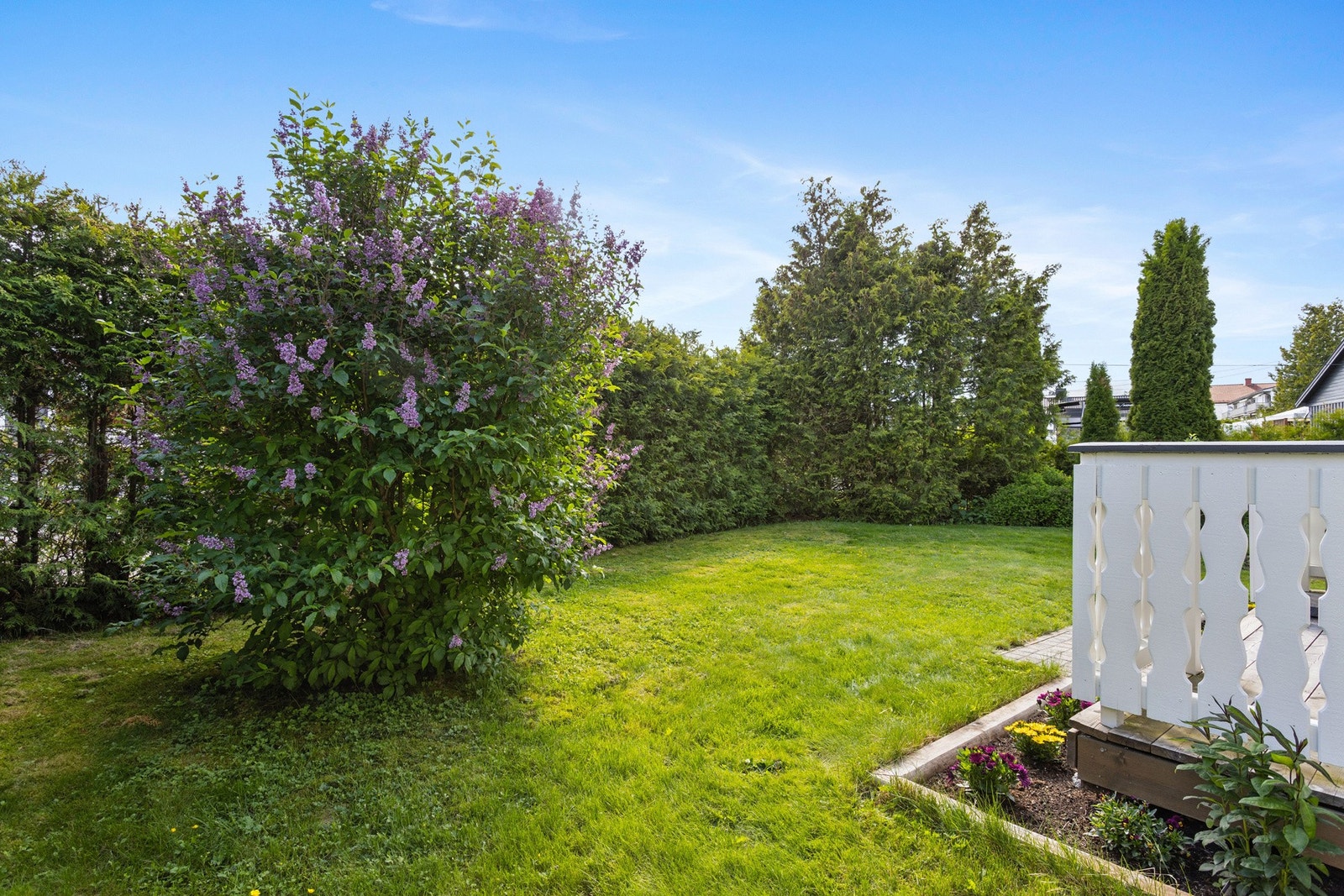 Den pent opparbeidede hagen med plen og beplantning skaper en grønn og privat ramme rundt eiendommen. Galleribilde