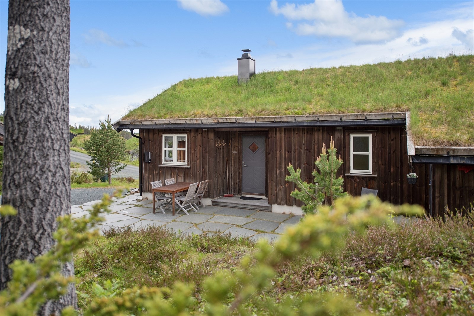Hytta har tradisjonell stående trekledning og torvtak. Galleribilde