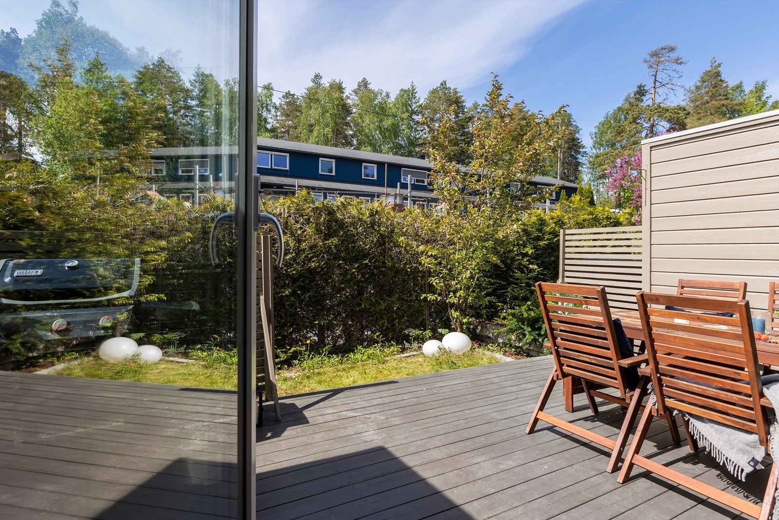 Utgang til opparbeidet med markterrasse, hageflekk med gressplen og en skjermende hekk. Galleribilde