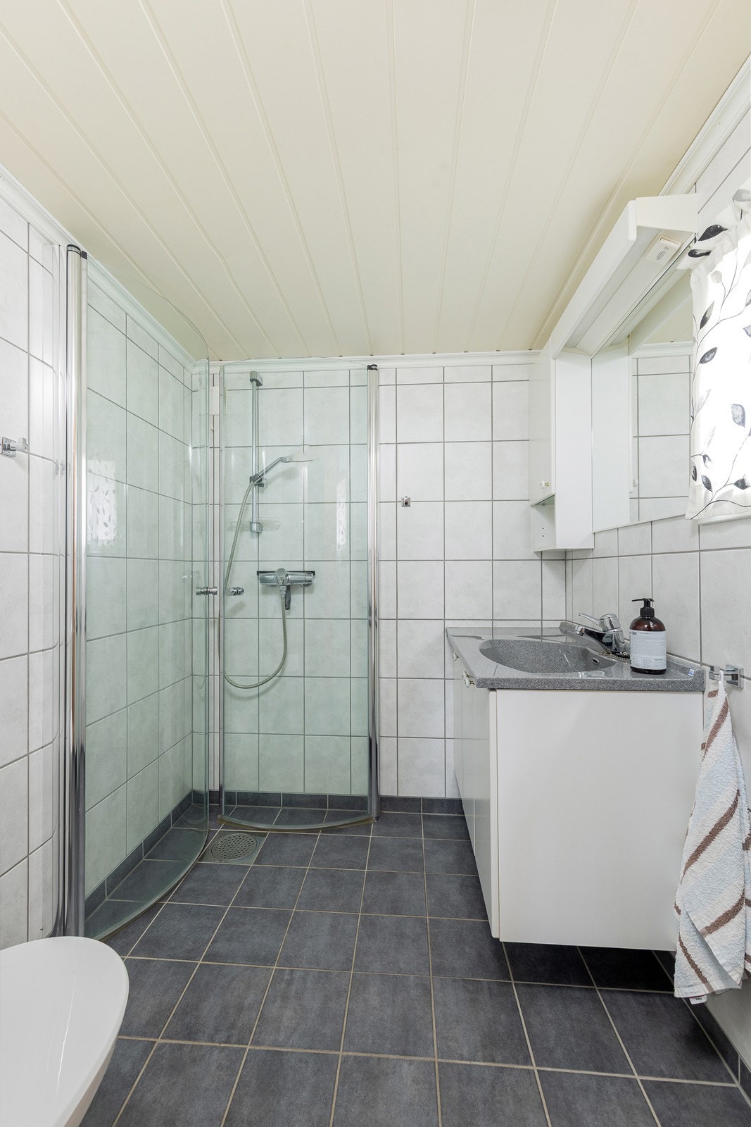 Badet er utstyrt med servantinnredning, toalett og hjørnedusj med glassdører. Galleribilde
