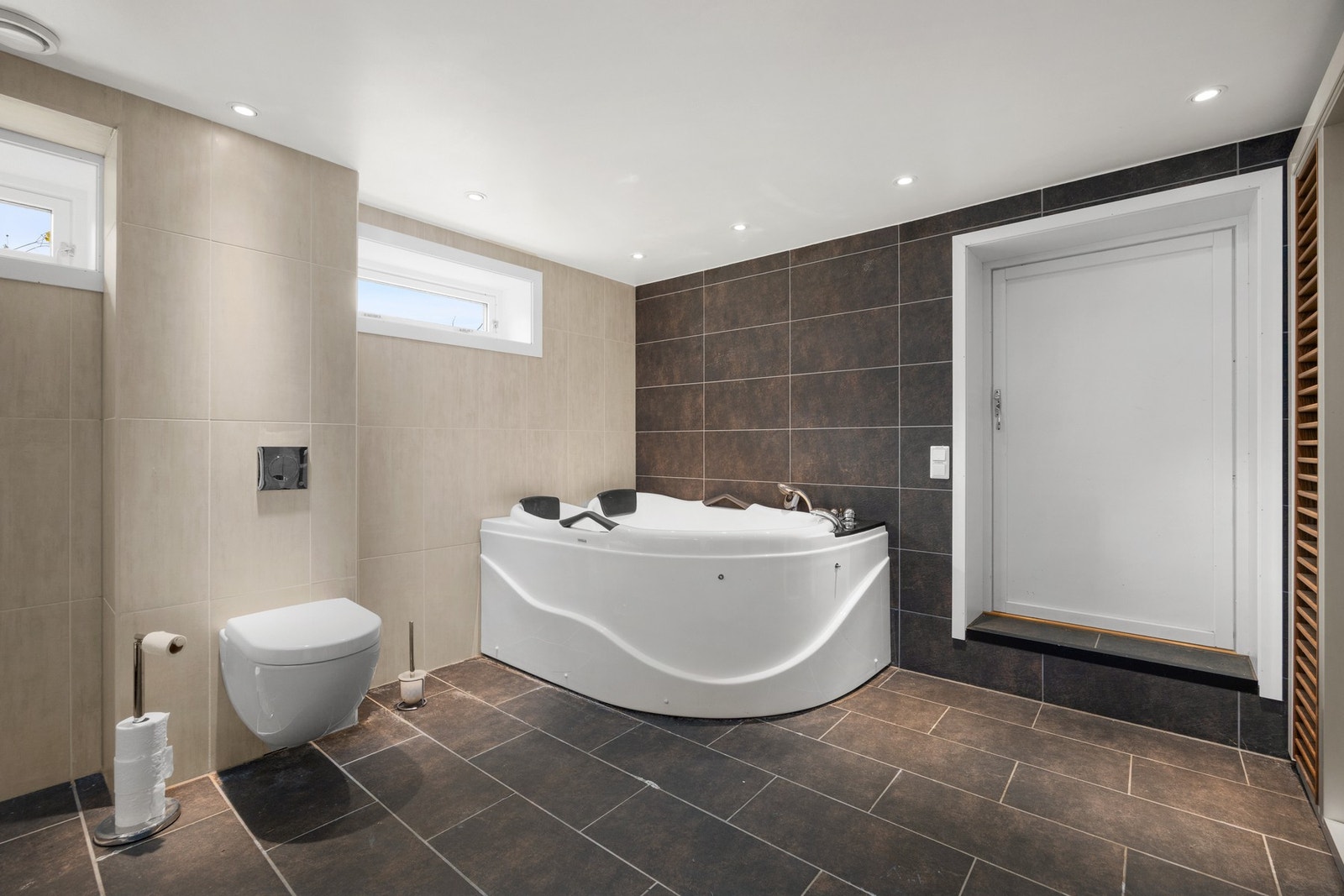 Badet er utstyrt med servantskap, veggmontert toalett og badekar. Galleribilde