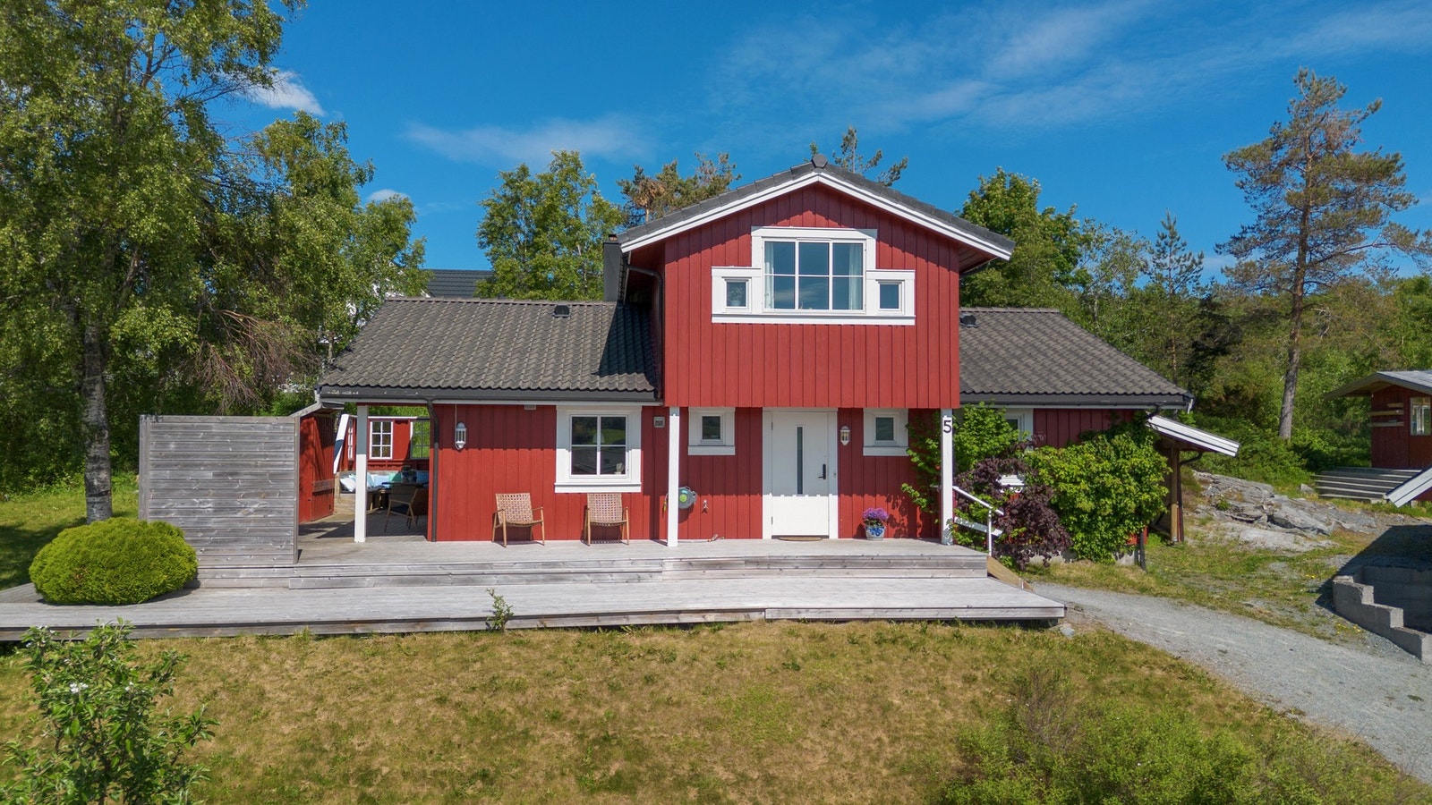 Tomten er opparbeidet med plen, parkeringsplasser, terrasser og beplantning Galleribilde