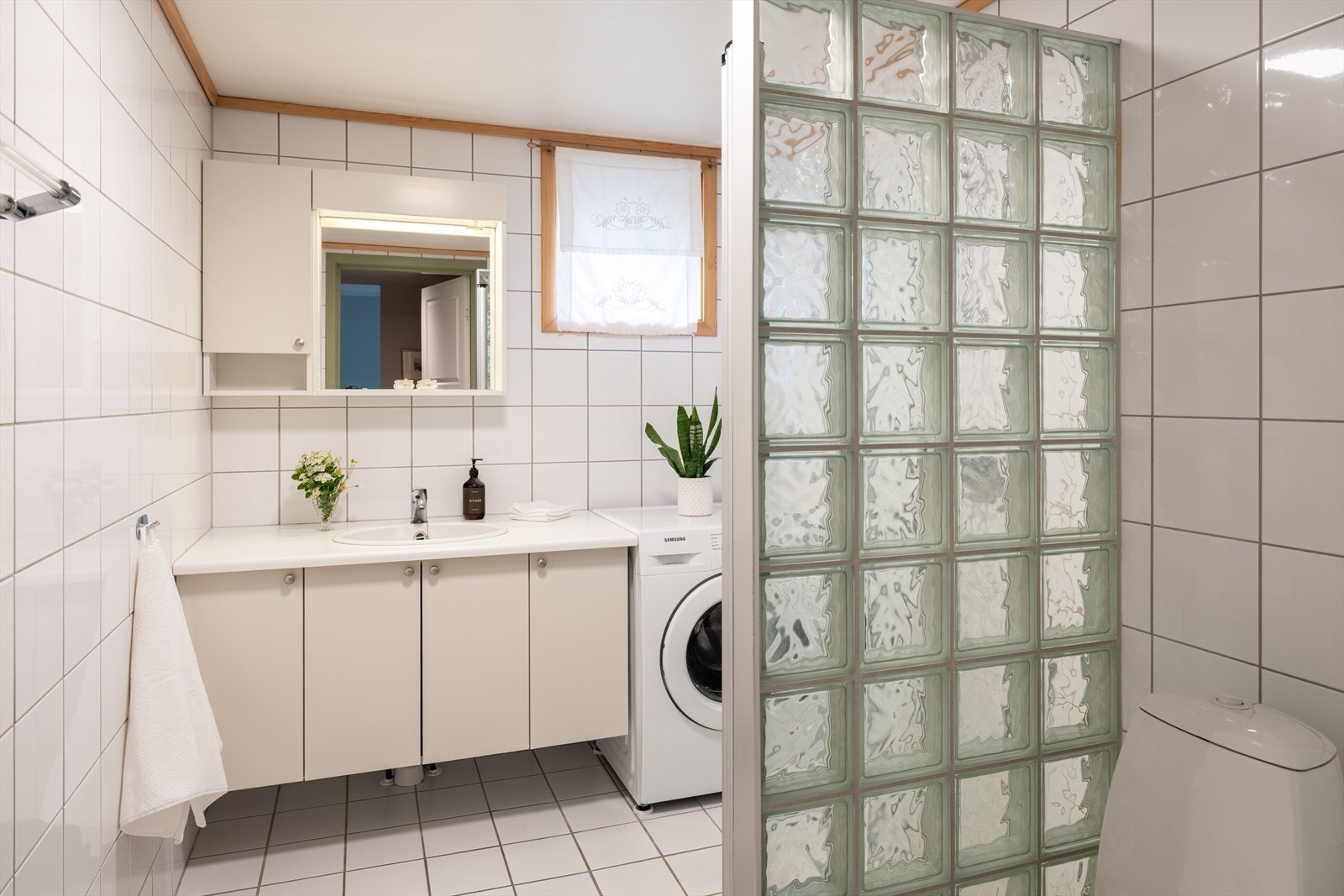 Baderommet er lyst med flislagte overflater, gulvvarme og opplegg til vaskemaskin. Galleribilde