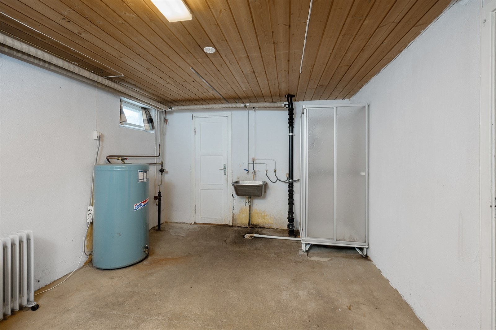Praktisk rom i kjelleren med plassering av varmtvannstank fra 1986. Her er det også sluk og opplegg for vaskemaskin. Galleribilde