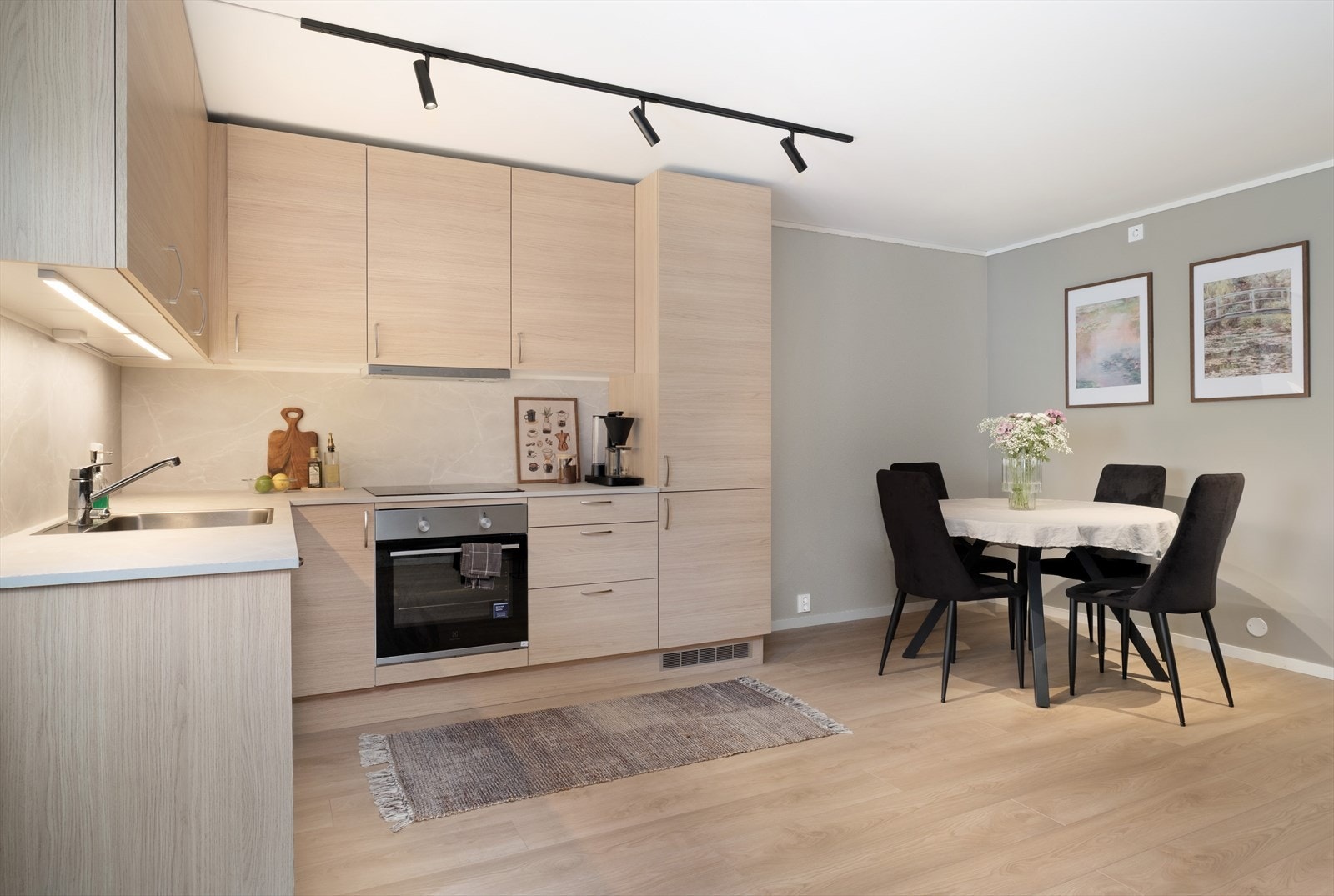 Kjøkenet har ei moderne innreiing med glatte frontar, laminatbenkeplate og laminat på veggen mellom benk og overskap. Galleribilde