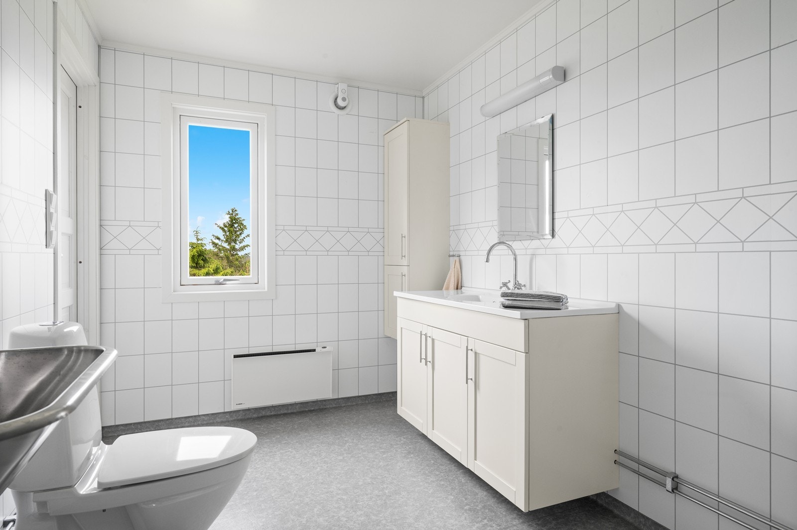 Rommet har baderomsplater på veggene og opplegg for vaskemaskin. Galleribilde
