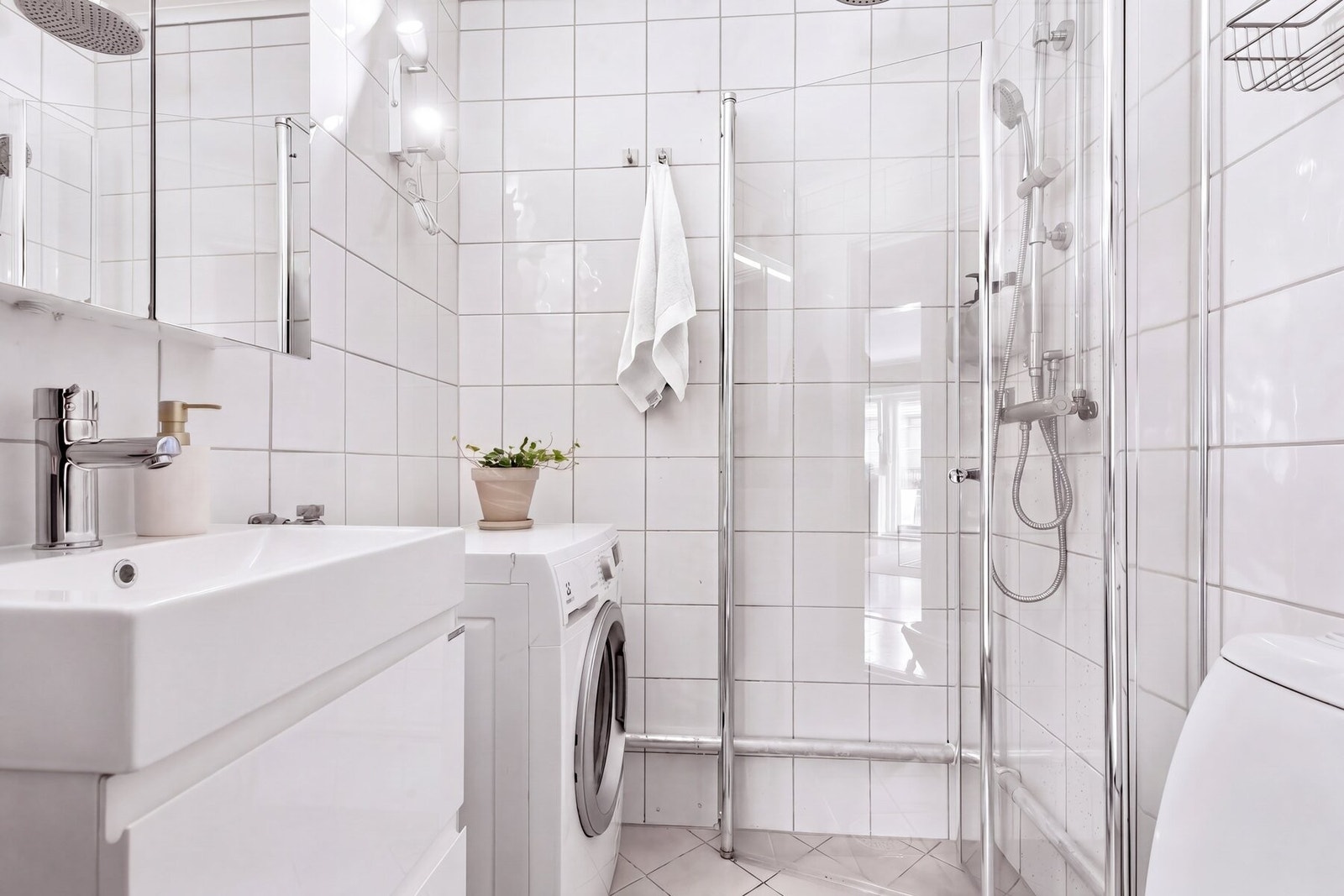 Badet er moderne og funksjonelt utstyrt med dusjnisje med innfellbare glassvegger som gir et stilrent uttrykk og effektiv plassutnyttelse. Opplegg for vaskemaskin. Galleribilde