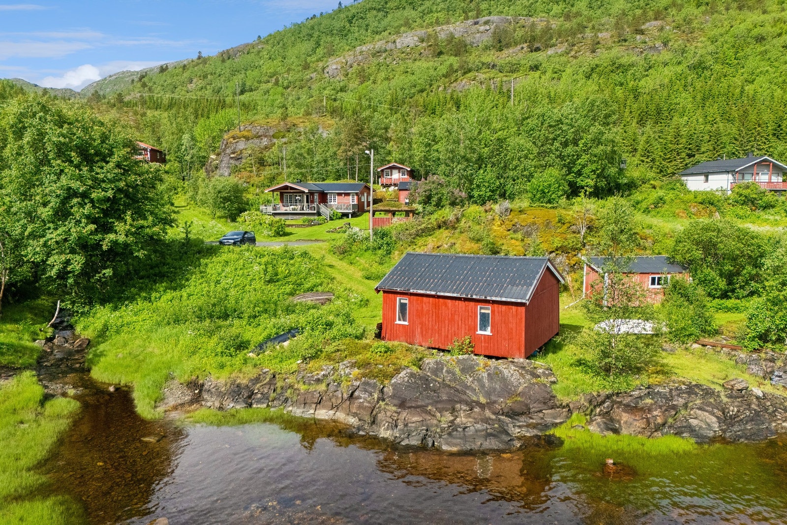 Eiendommen ligger skjermet til i grønne omgivelser, med andel i naust ved sjøen. Galleribilde