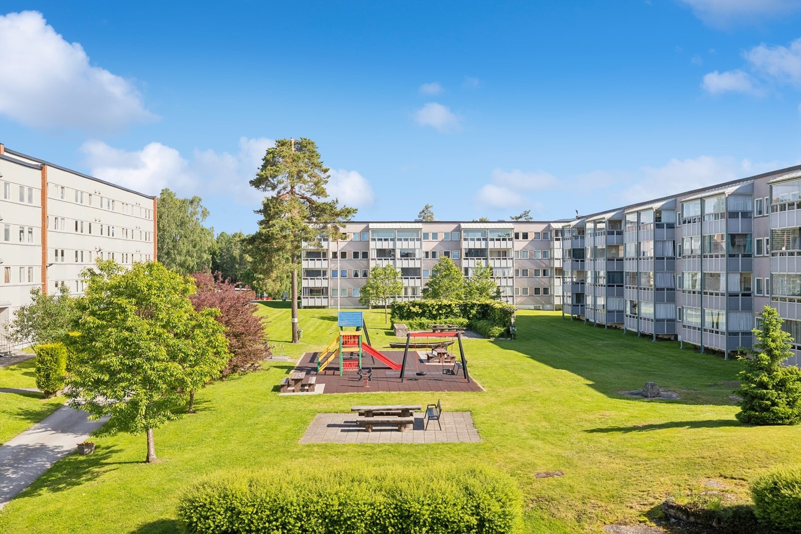 Velstelt fellesareal med lekeplass og tilrettelagte sitteplasser - et hyggelig område for både lek og opphold. Galleribilde