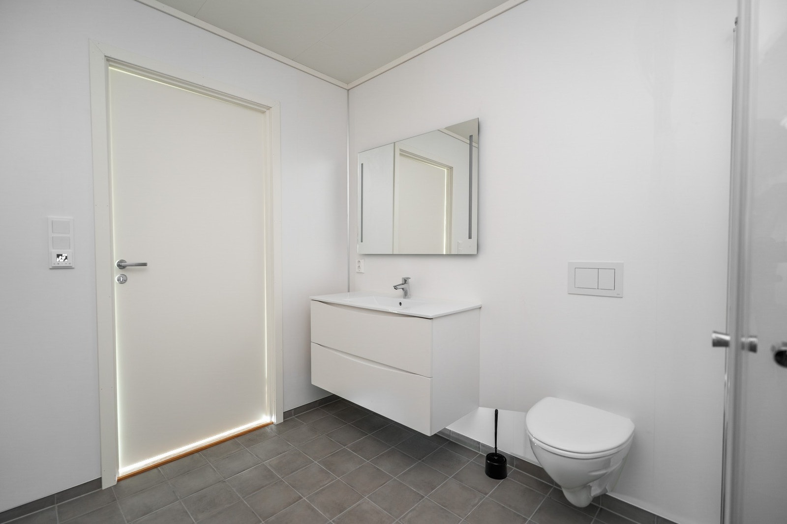 Badet er utstyrt med nedfelt servant, veggmontert toalett,
dusjvegger/hjørne og opplegg for vaskemaskin Galleribilde