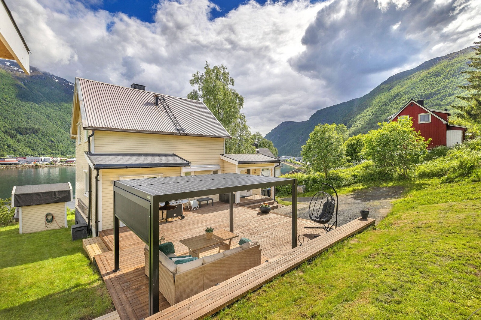 Eiendommen har en pent opparbeidet tomt med plen beplantninger og markterrasse med pergola Galleribilde