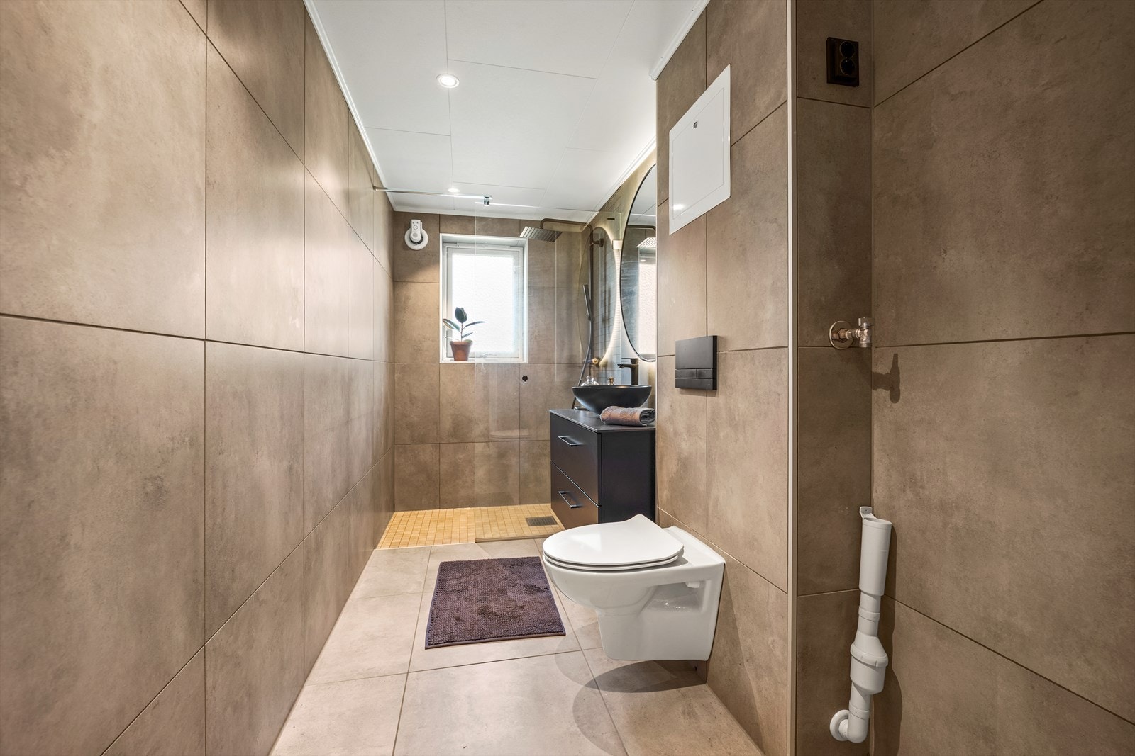 Moderne baderom med store fliser. Badet ble modernisert i 2022 i regi av borettslaget. opplegg for vaskemaskin. Galleribilde