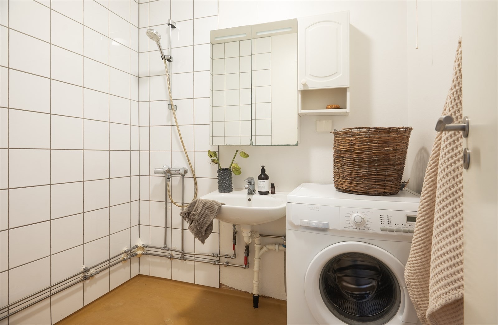 Funksjonelt men eldre baderom. Badet inneholder servant, speilskap, dusjhjørne med forheng og opplegg for vaskemaskin. Mulighet for tørketrommel om skap på vegg fjernes Galleribilde