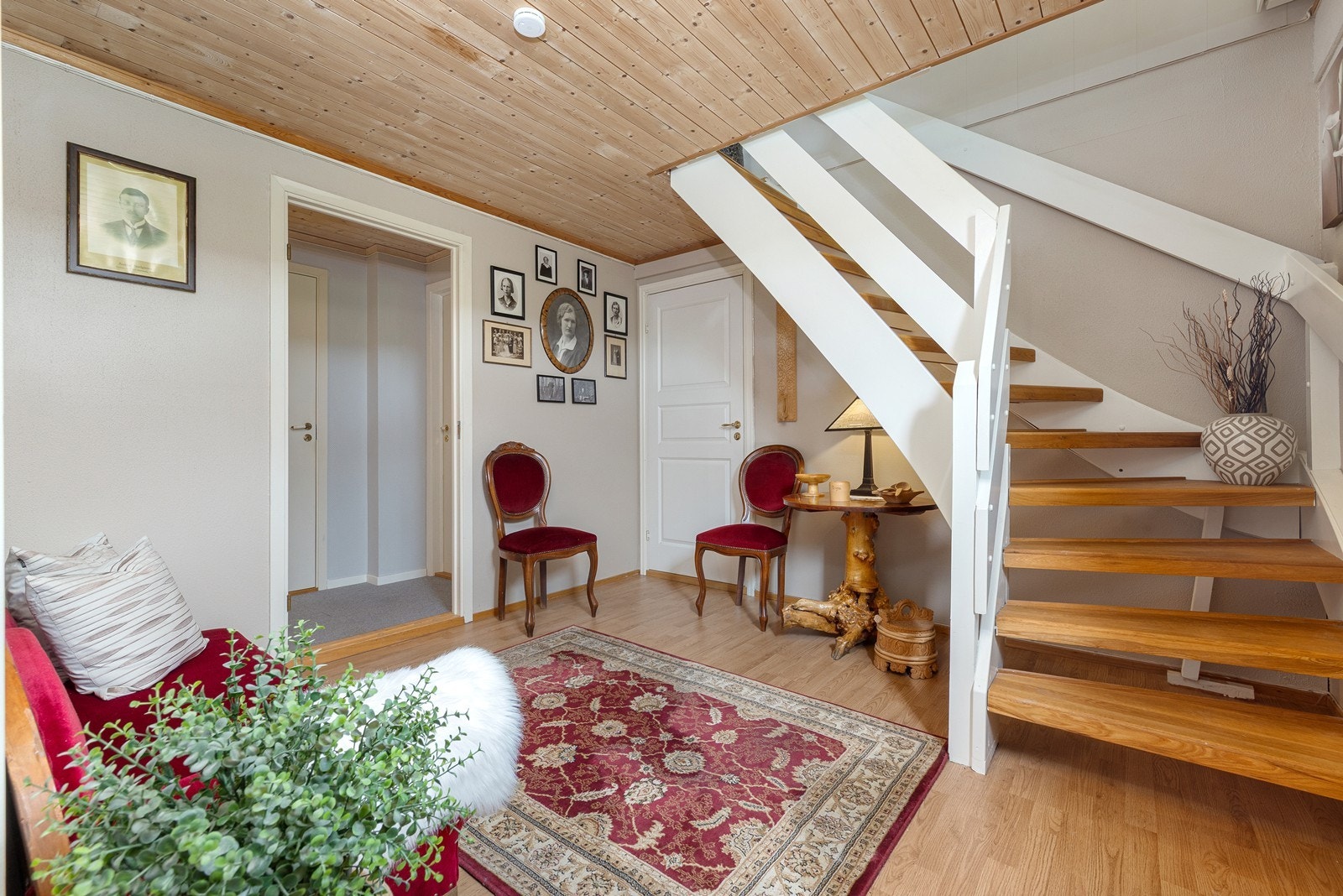 Gang i kjelleretasjen med lakkert tretrapp som forbinder de to planene. Galleribilde