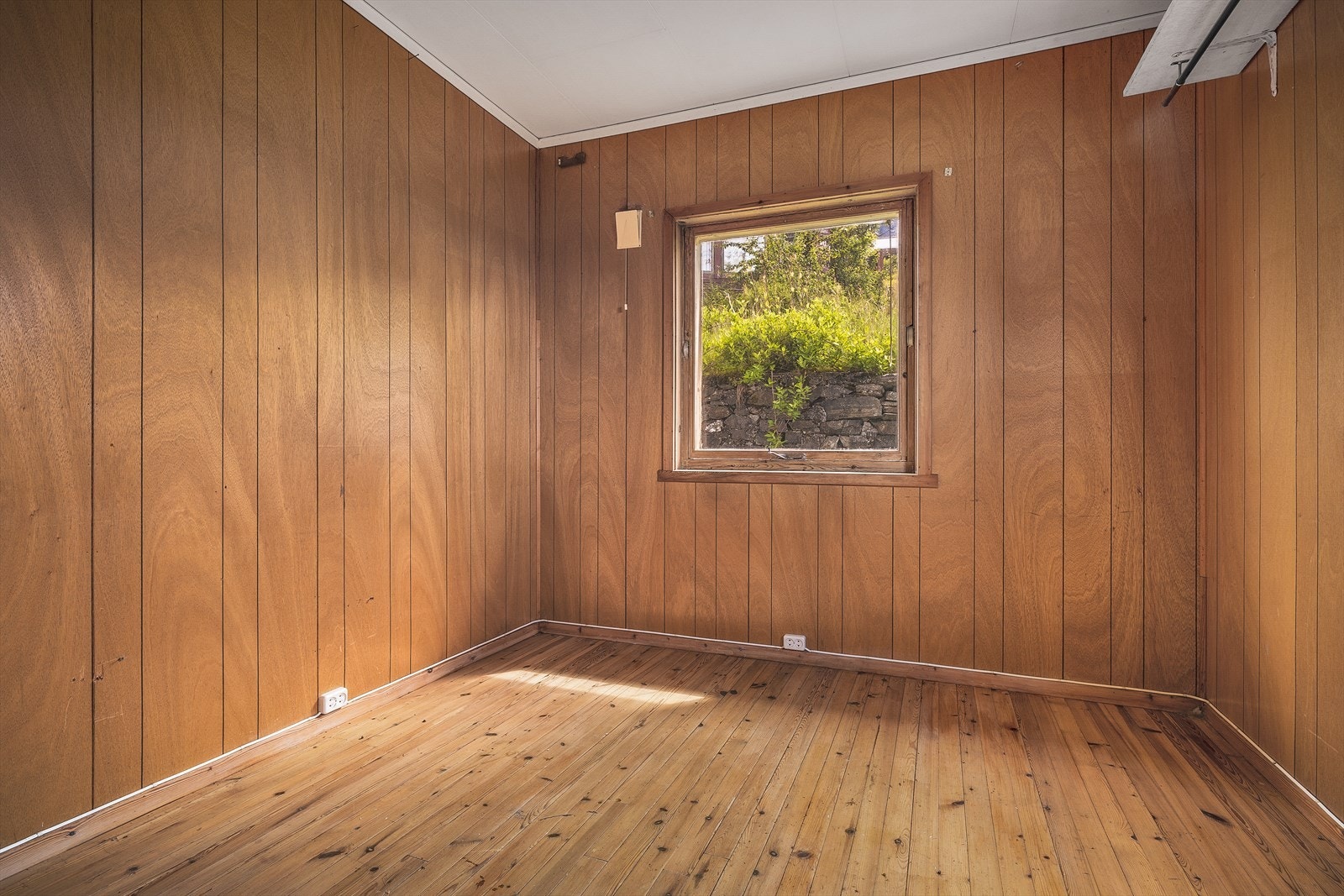 Ett av soverommene har furubord på gulvet og tynnpanel på veggene. Galleribilde
