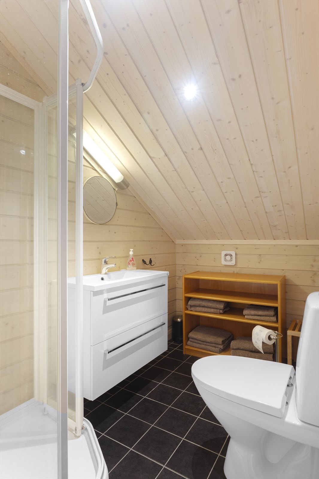 Badet i loftsetasjen har dusjkabinett, toalett og vask med underskap. Vegger og himling er av trepanel, og gulvet er flislagt. Galleribilde