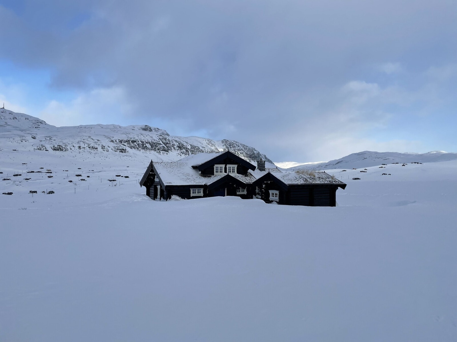 Hytta speiler seg med snødekte fjell også. Bilde fra selgers arkiv. Galleribilde