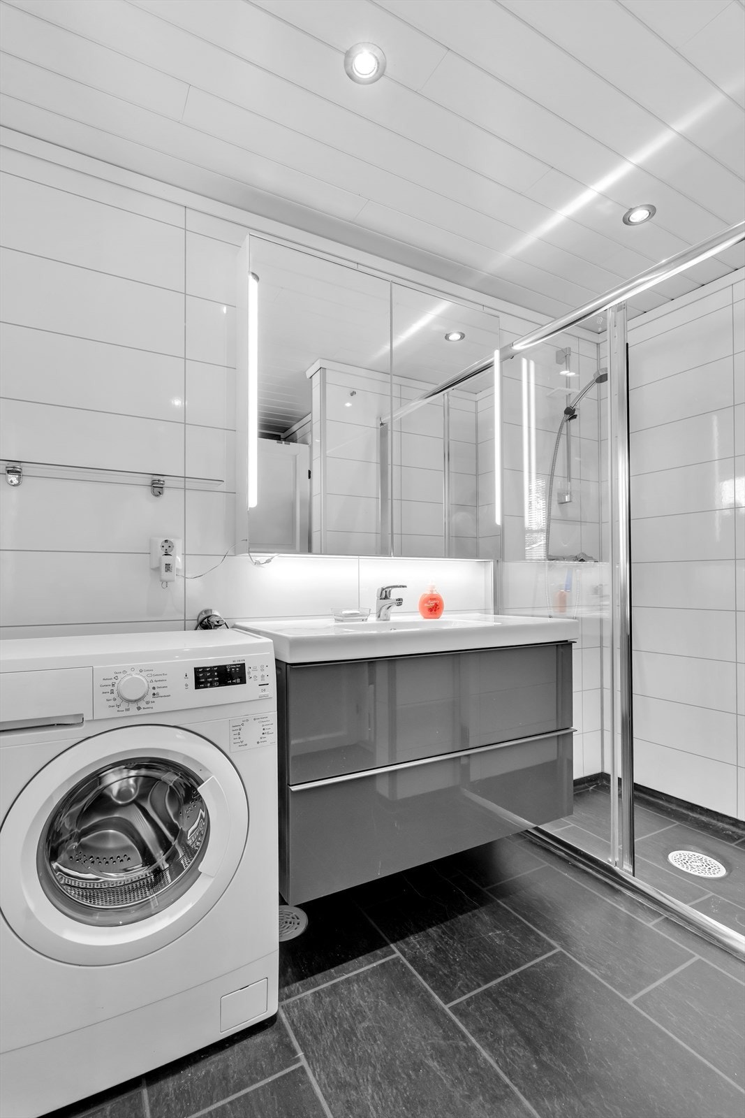 Badet er utstyrt med dusjhjørne, servantinnredning og opplegg for vaskemaskin. Galleribilde