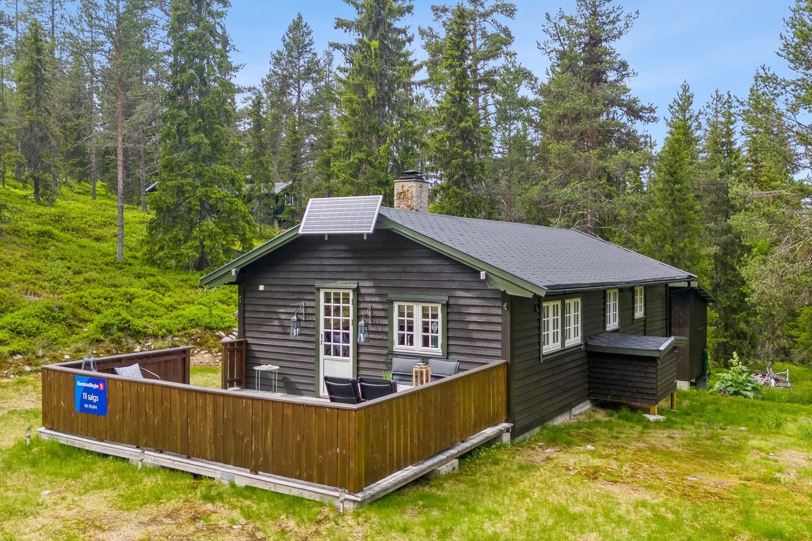 Sjarmerende hytte i naturskjønne omgivelser med solcellepanel, stor terrasse og umiddelbar nærhet til tur- og friluftsområder. Galleribilde