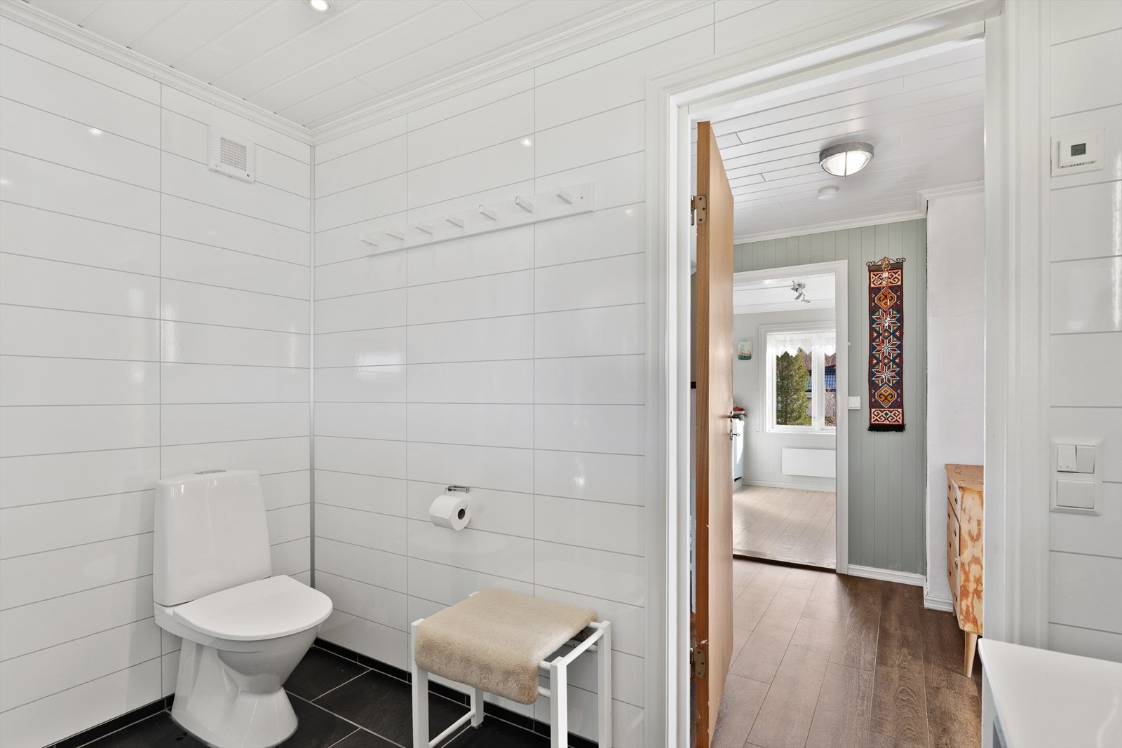 Badet har fliser på gulv og baderomsplater på vegg Galleribilde