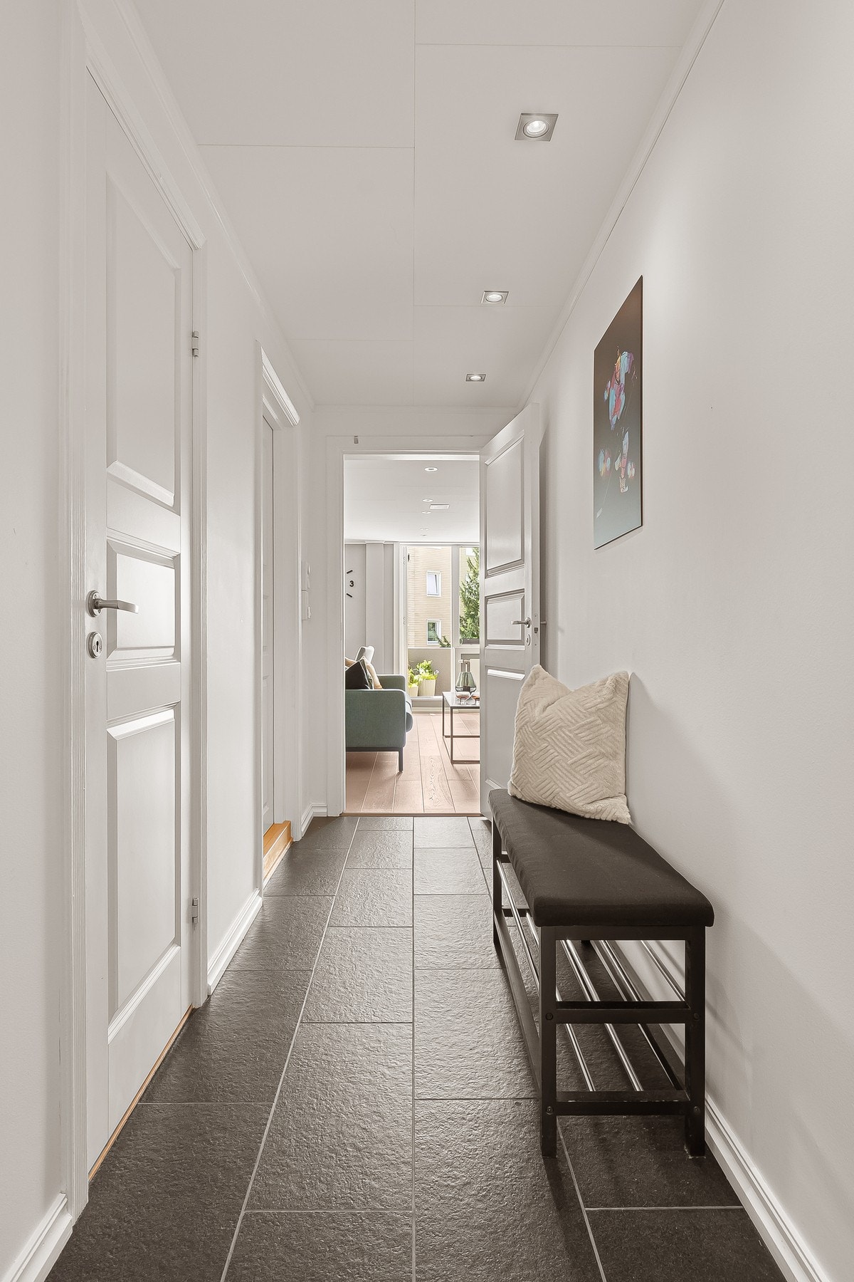 Lys og romslig entré med flis på gulv, malt overflate på vegger og downlights i himling. Galleribilde