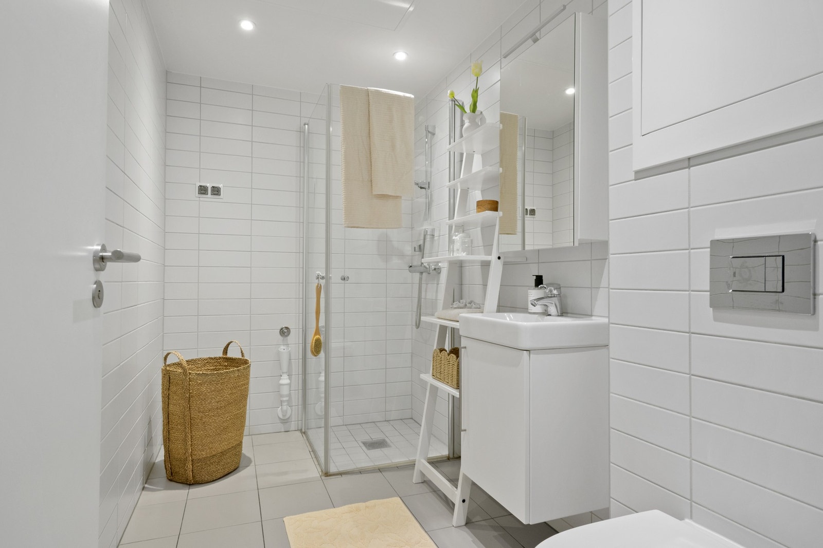 Badet er flislagt og har elektrisk gulvvarme, dusjdører, servantinnredning og opplegg for vaskemaskin. Galleribilde