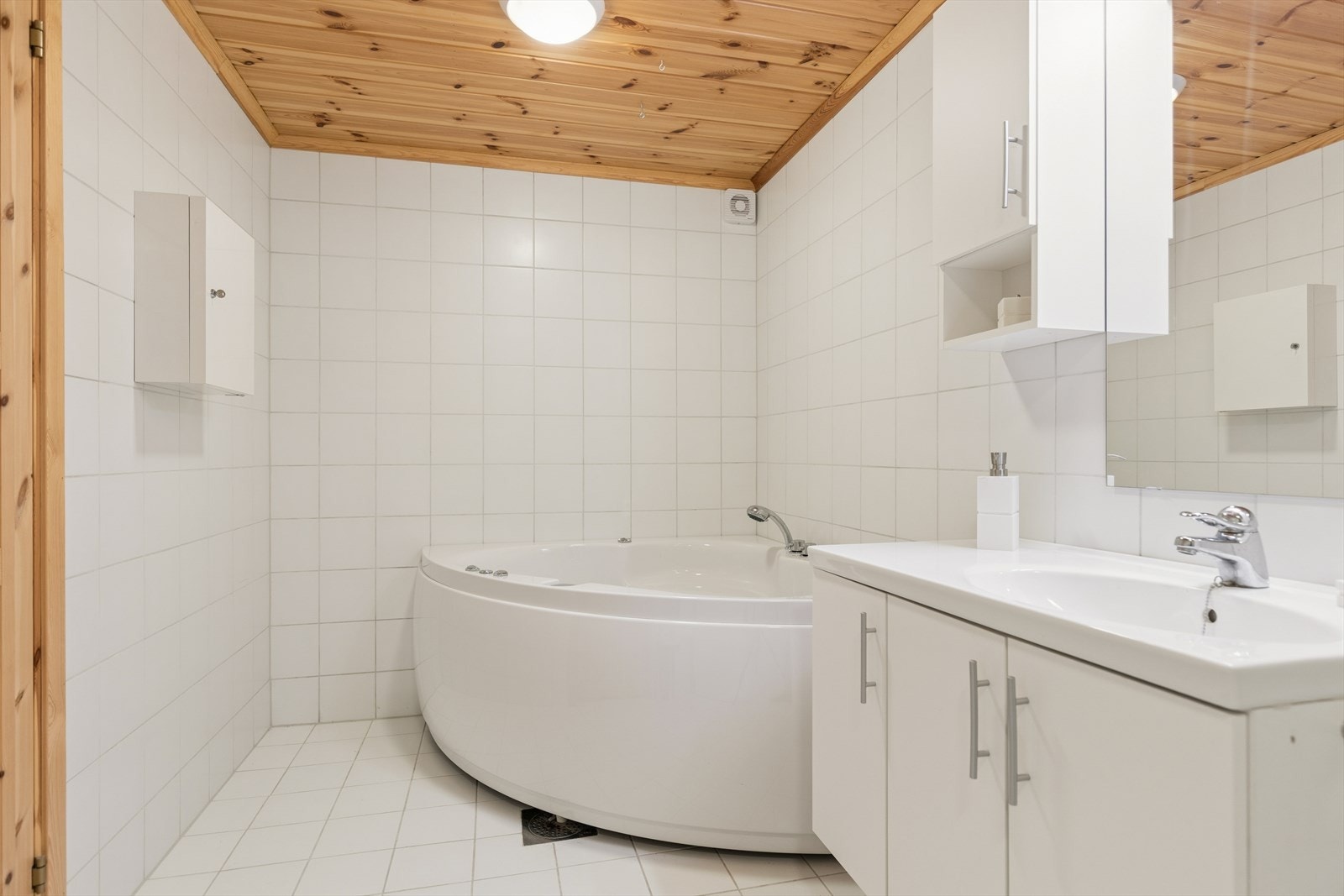 Romslig bad med gjennomgående lyse flislagte vegger og gulv som gir et rent og tidløst uttrykk. Galleribilde