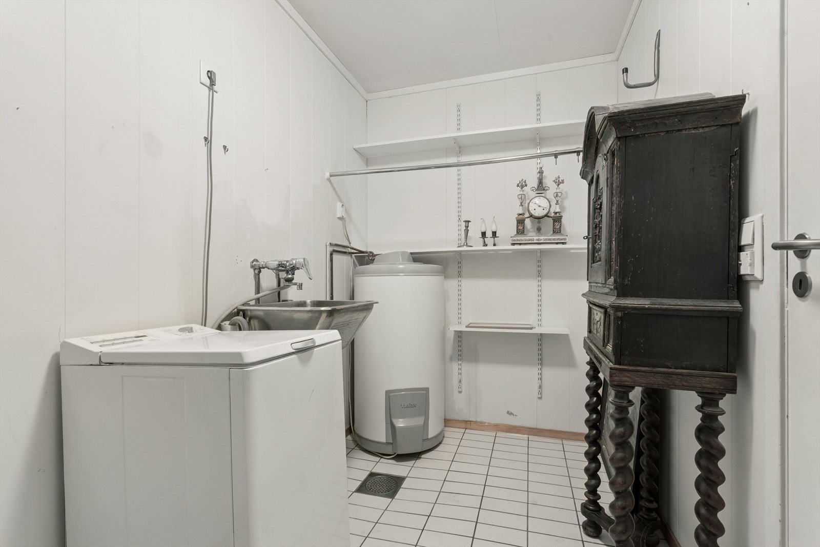 Vaskerom med opplegg for vaskemaskin, utslagskum og hyller som gir praktisk oppbevaringsplass. Galleribilde