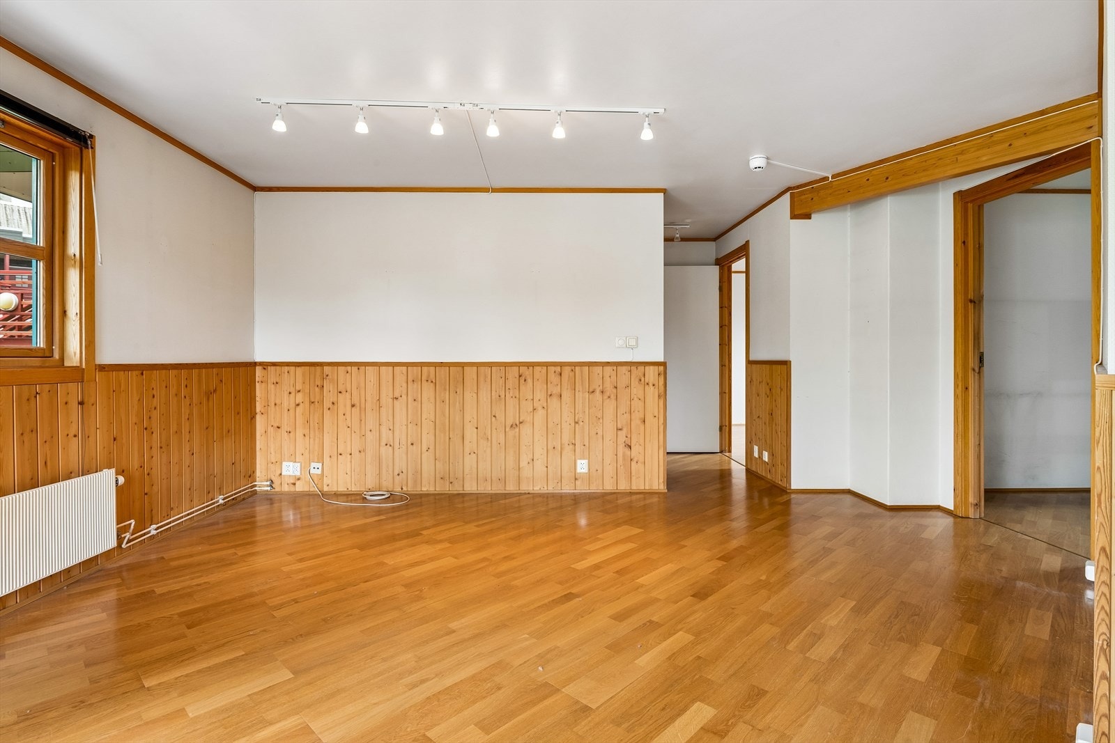 Stuen har parkett på gulv og vegger med en kombinasjon av trepanel og tapet. Galleribilde
