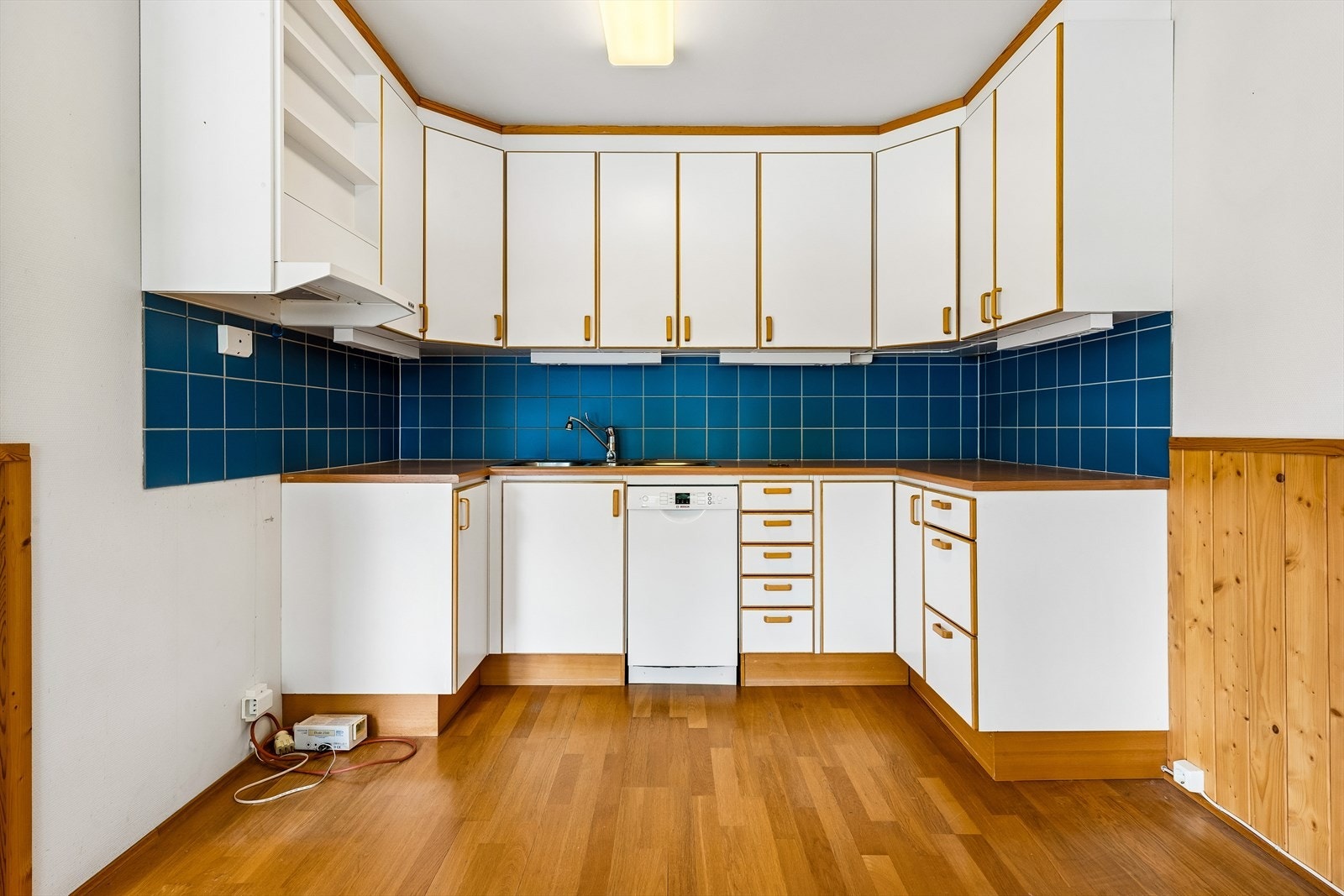 Kjøkkeninnredning med glatte fronter og laminat benkeplate. Det er fliser over benken og opplegg for oppvaskmaskin. Galleribilde