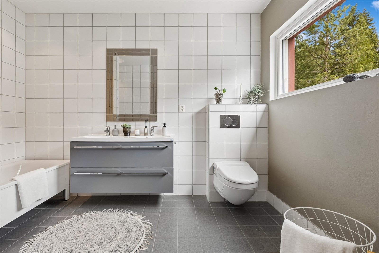 Badet har stort vindu som gir nærhet til naturen og null naboer. Her er det både badekar og egen dusj, vannspyletoalett (vanndusj og lufttørk) fra Geberit og praktisk innredning med store skuffer. Galleribilde