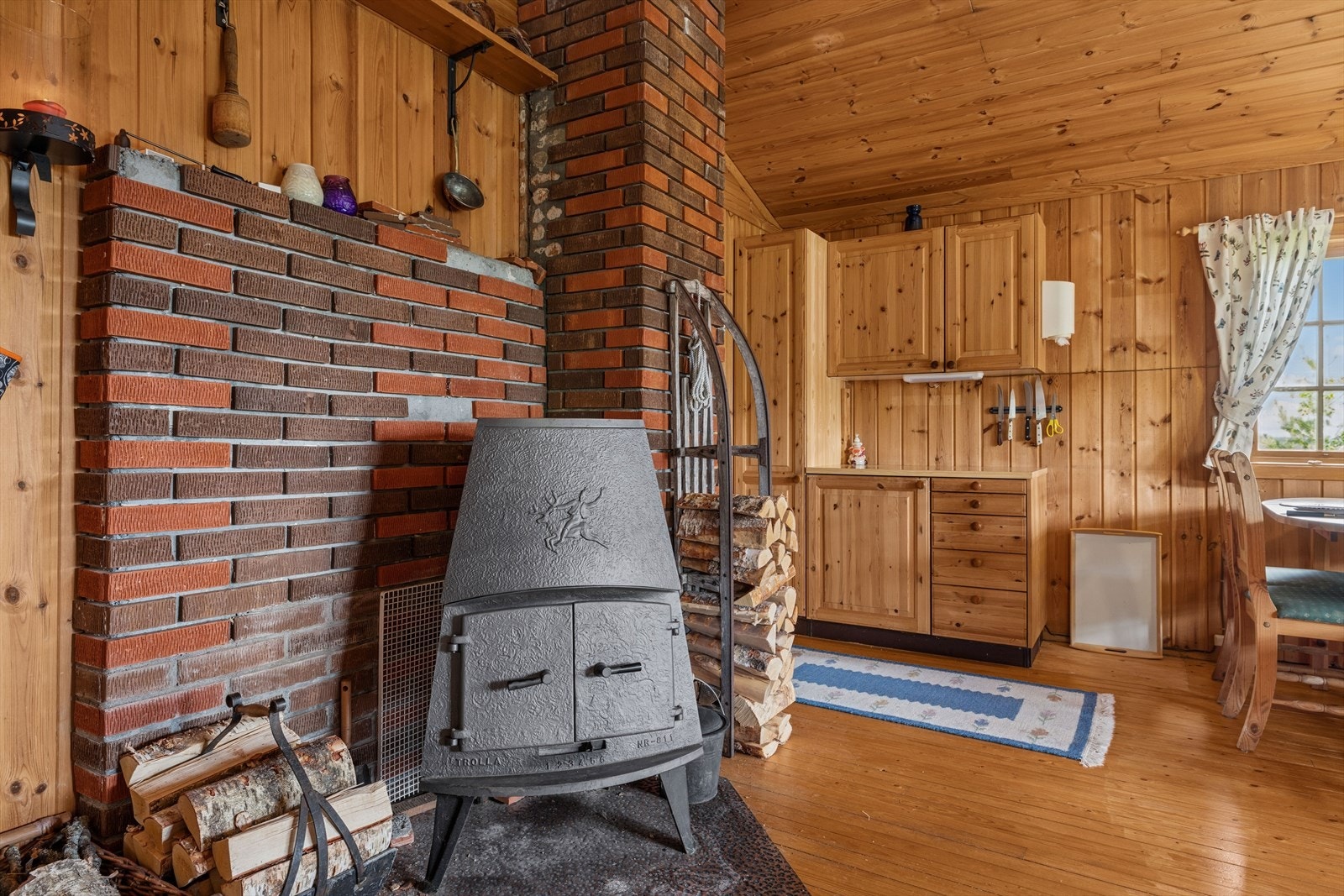 Vedovnen, som er plassert på kobberplate foran teglsatt pipe og bidrar til en tradisjonell og sjarmerende hyttestemning. Galleribilde