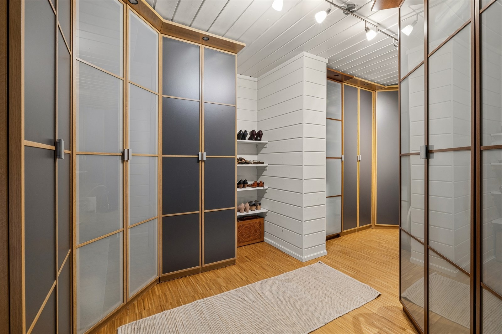 I underetasjen er det en egen garderobe med omfattende garderobeløsninger montert langs veggene - skap med glassfronter og trerammer gir god kapasitet til oppbevaring. Galleribilde
