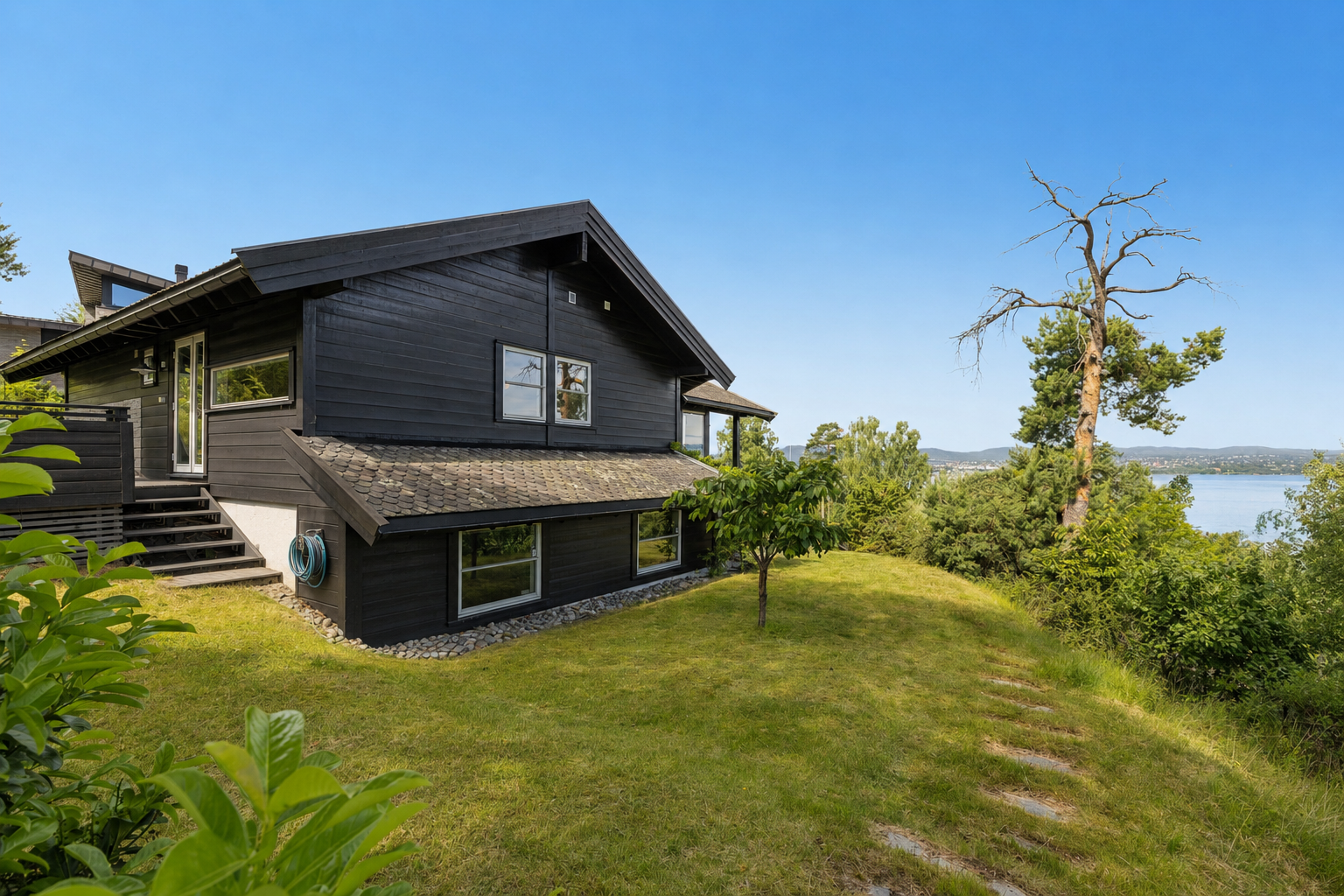 En idyllisk og romslig hage med god plass til lek og utfoldelse - et perfekt uteområde hvor barn kan boltre seg fritt i naturskjønne omgivelser. Galleribilde