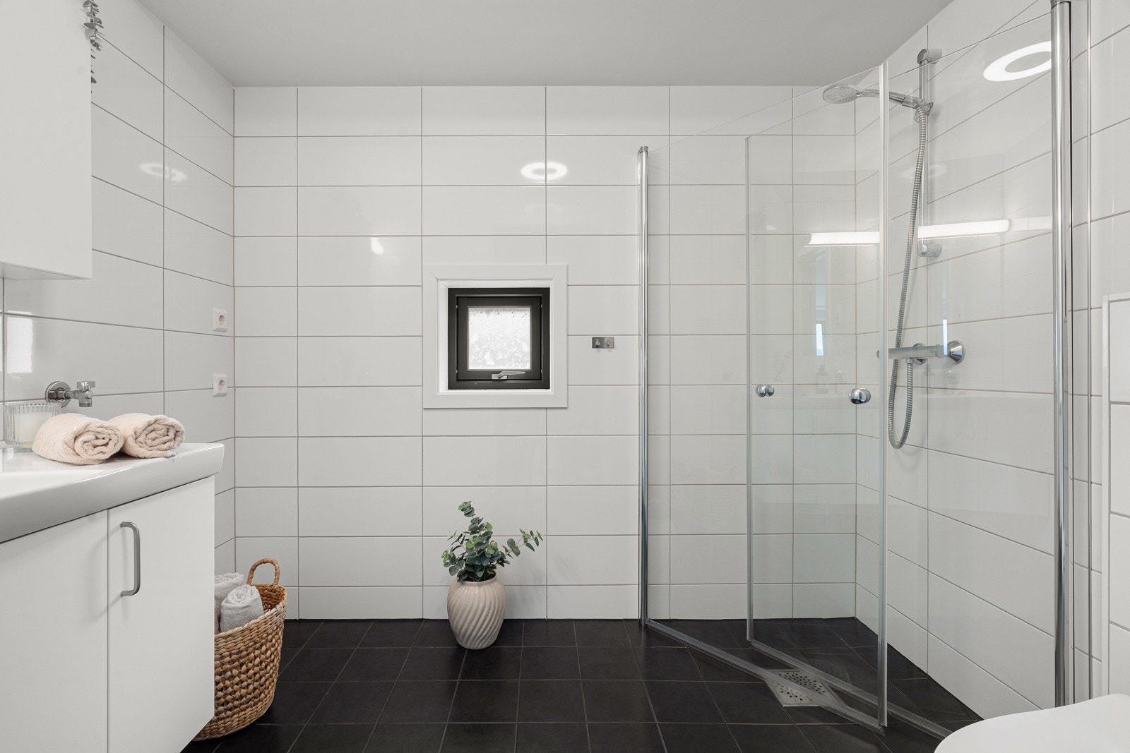 Innbydende flislagt baderom med varme i gulv, ellers er badet utstyrt med dusjhjørne, servantskap og plass til vaskemaskin og tørketrommel.