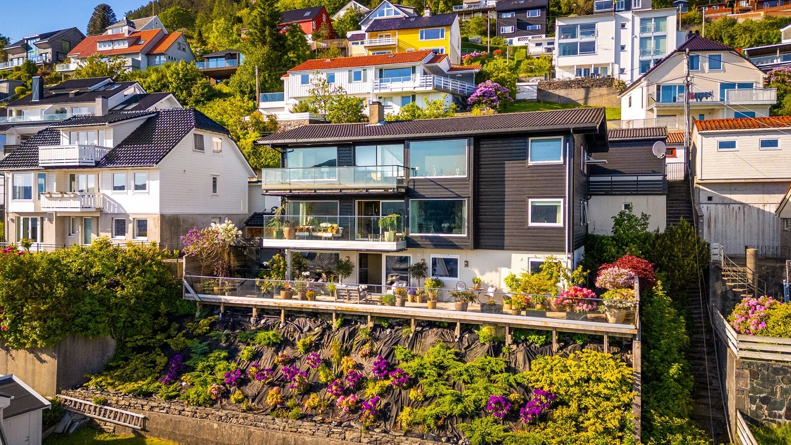 Leiligheten strekker seg over de to nederste etasjene. Skråningen under beplantet med lavtvoksende planter i 2023, og de skal dekke hele området med tiden. Galleribilde