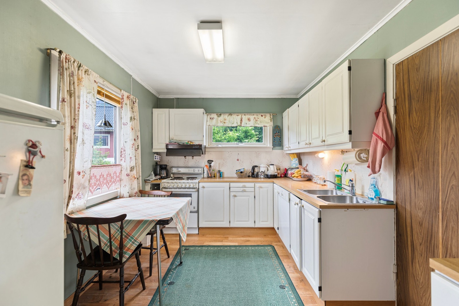 Kjøkkenet er utstyrt med ventilator over komfyr, opplegg for oppvaskmaskin og laminat benkeplate med nedfelt dobbel oppvaskkum. Galleribilde