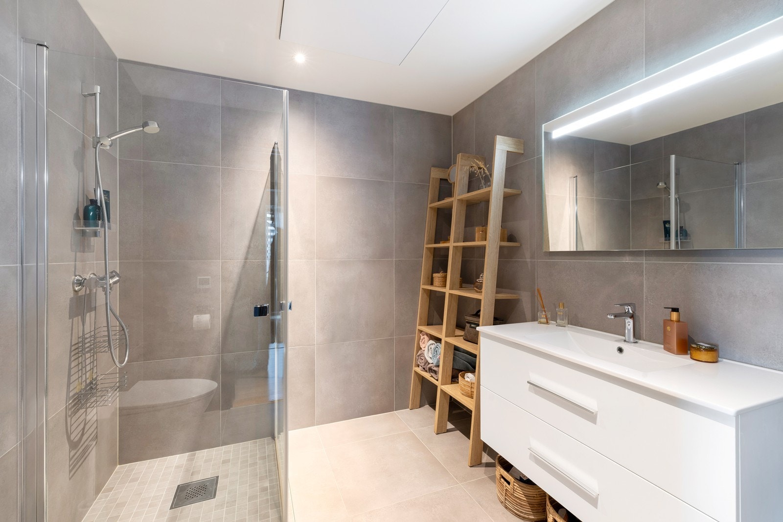 Lekkert flislagt bad med varme i gulv. Badet har dusjhjørne, vegghengt toalett og servant med underskuffer. Galleribilde