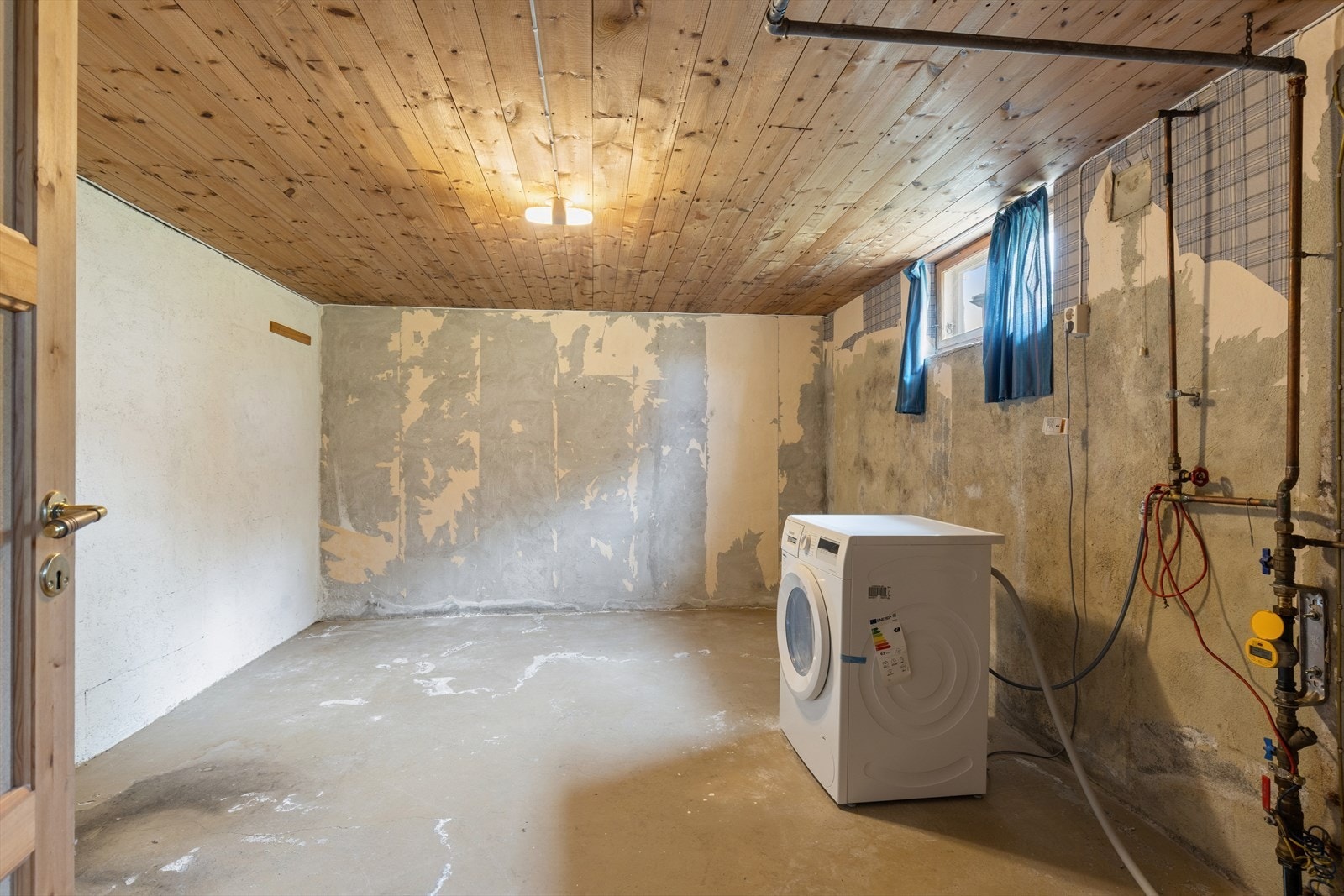 Romslig vaskerom i kjeller med betonggulv og opplegg for vaskemaskin. Galleribilde
