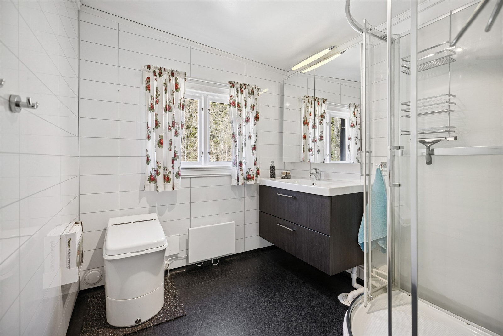 Lyst og trivelig bad med dusjkabinett, moderne servantinnredning, speilskap og forbrenningstoalett. Galleribilde