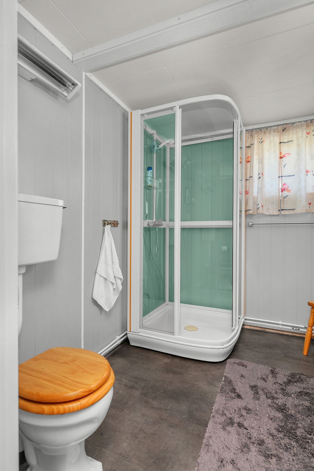 Badet har innredning med servant og underskap, dusjkabinett og toalett Galleribilde